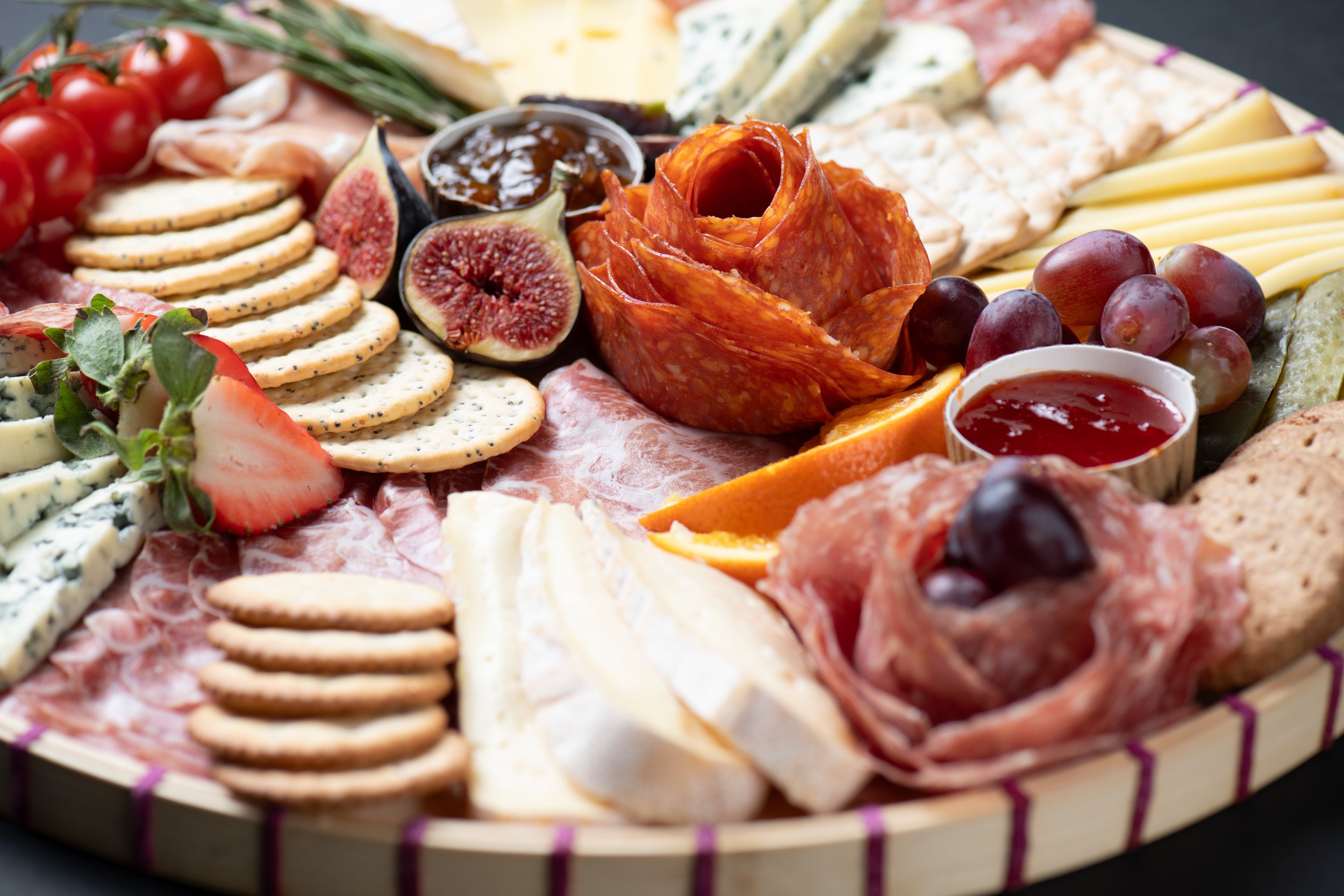 Charcuterie board with assorted meats, cheeses, crackers, fruits, and condiments
