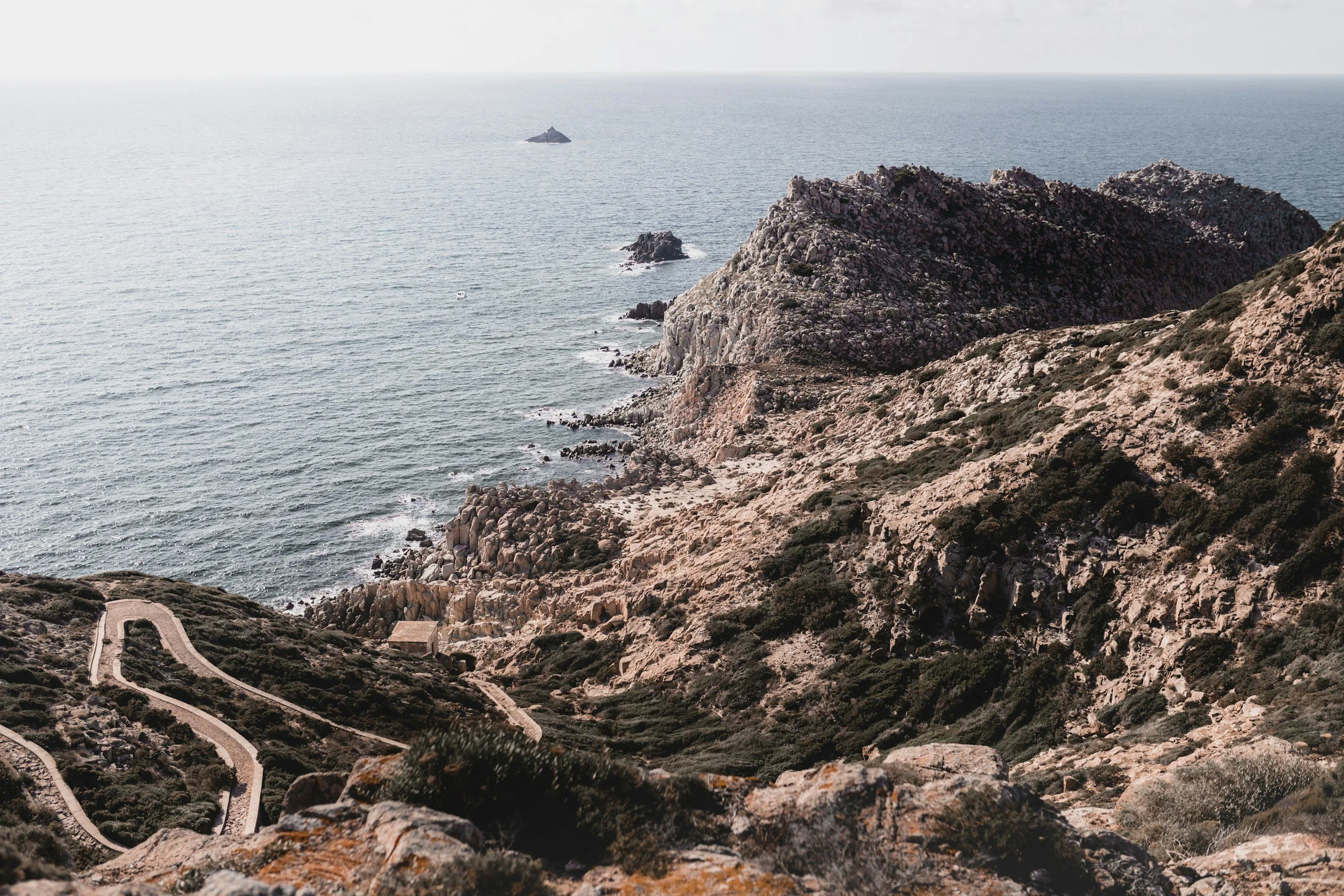 Rocky coastline with winding paths, ocean view, and distant rocky islets