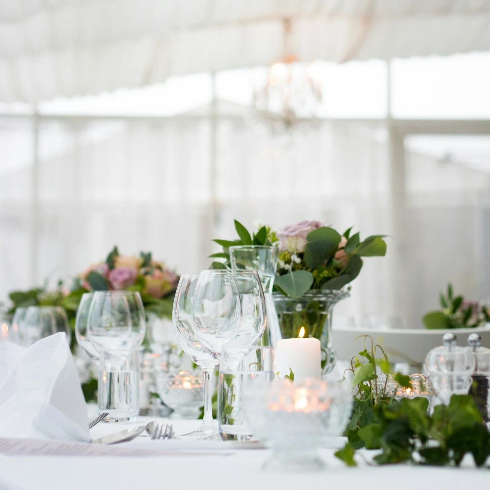 Elegant table setting with glassware, candles, and floral centerpiece at a wedding reception.