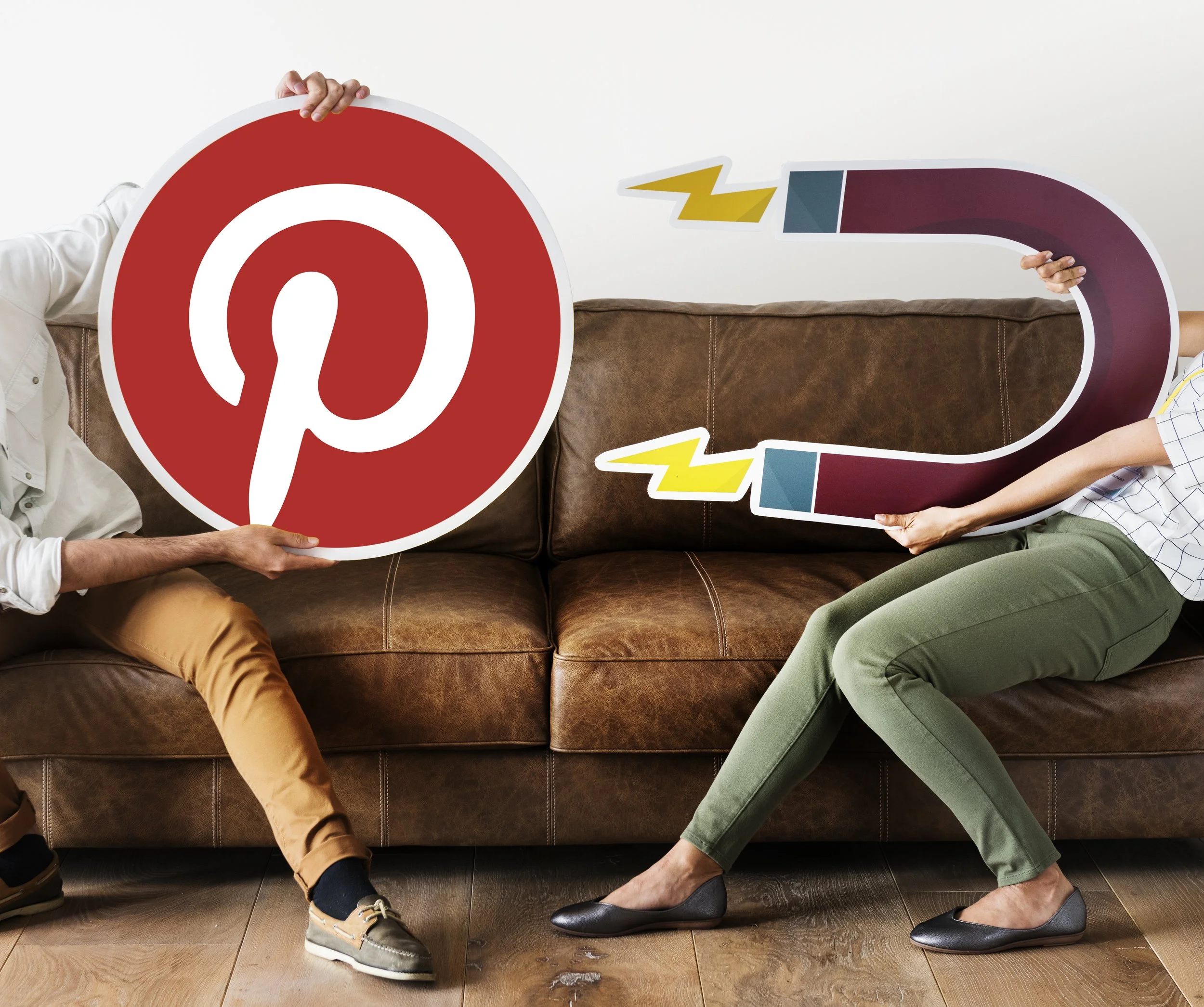 Someone holding a Pinterest sign logo and another person holding a magnet icon to represent traffic to Pinterest