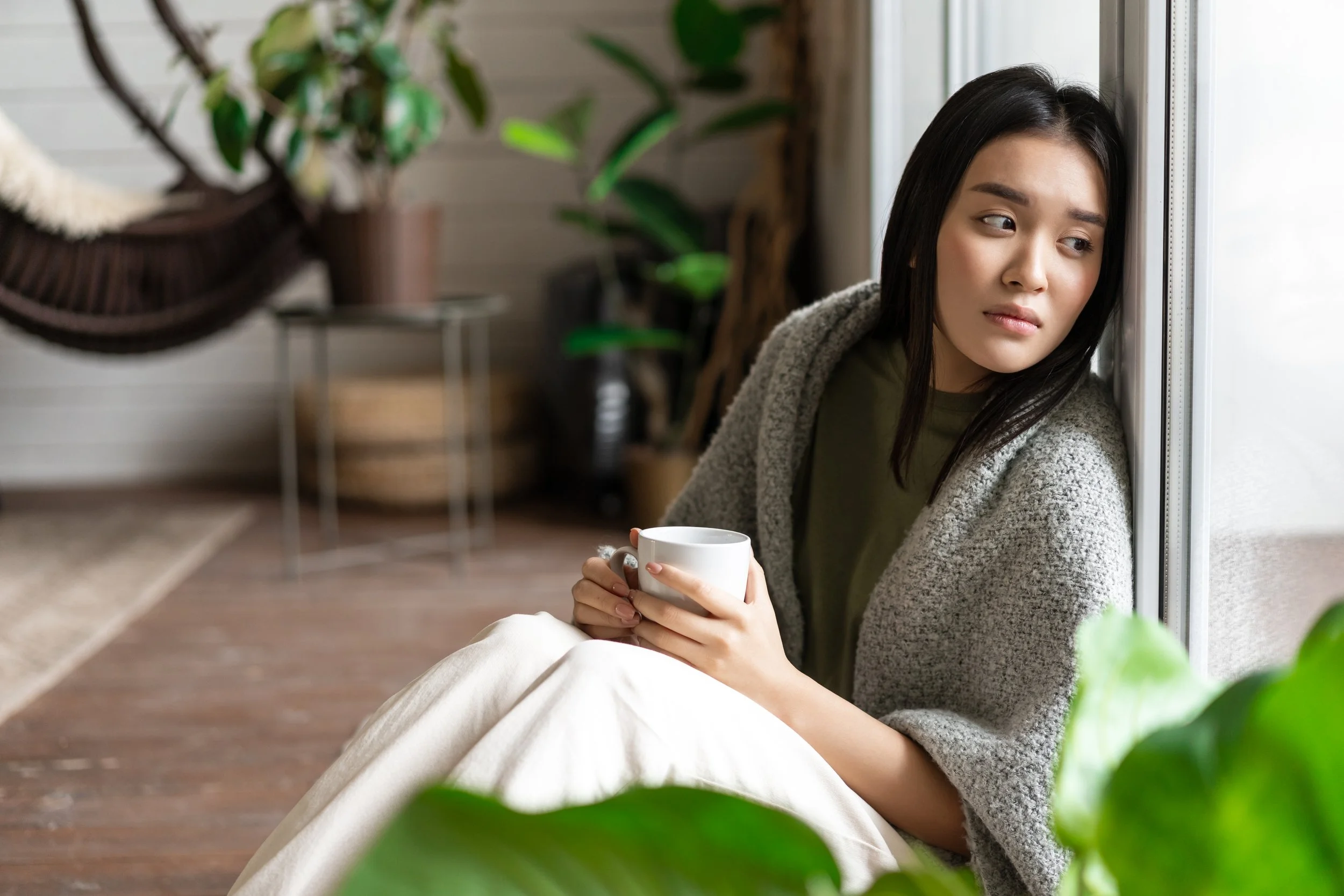 an introvert Asian woman looking out the window