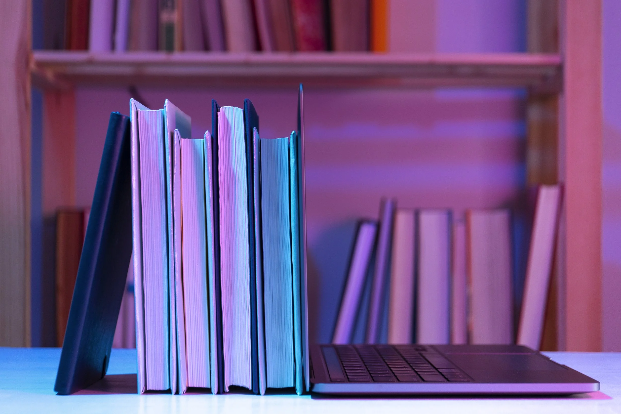 books sitting up with a laptop leaned next to  it