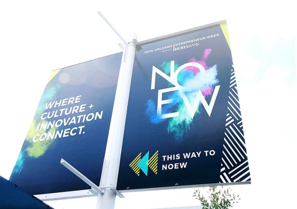 A large outdoor signboard promoting New Orleans Entrepreneur Week by Iberiabank with colorful splashes and the slogan, 'Where culture + innovation connect.'