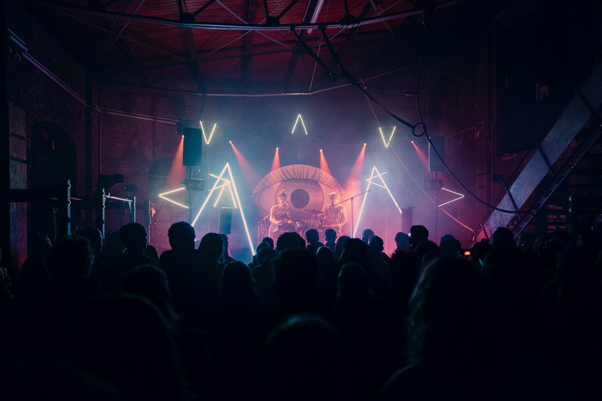 stage with two artist in colorful lights in the distance