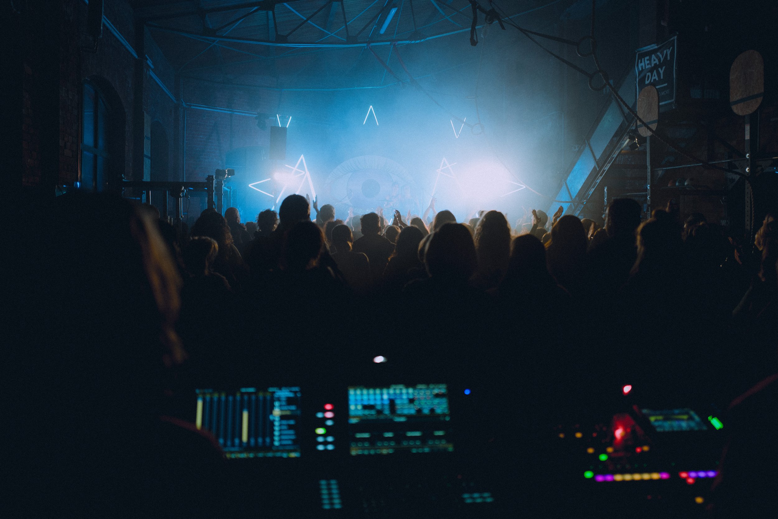 concerthall filled with people covered in beautiful colorful lights and audiotech in foreground