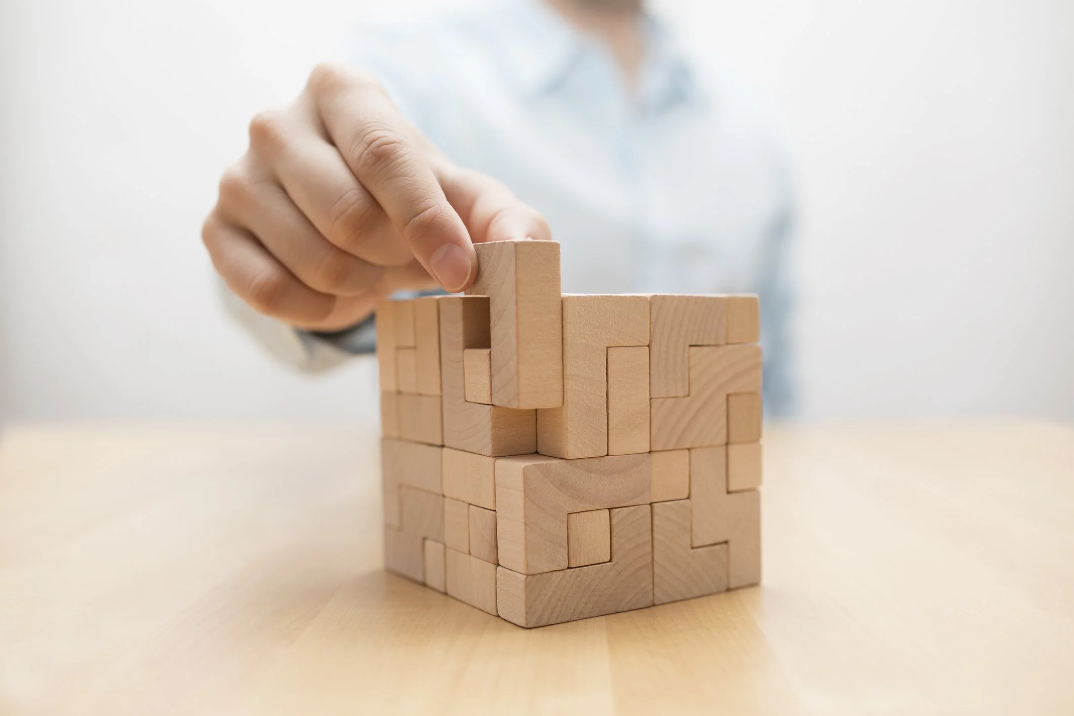 A person stacking wooden blocks to form a tower.