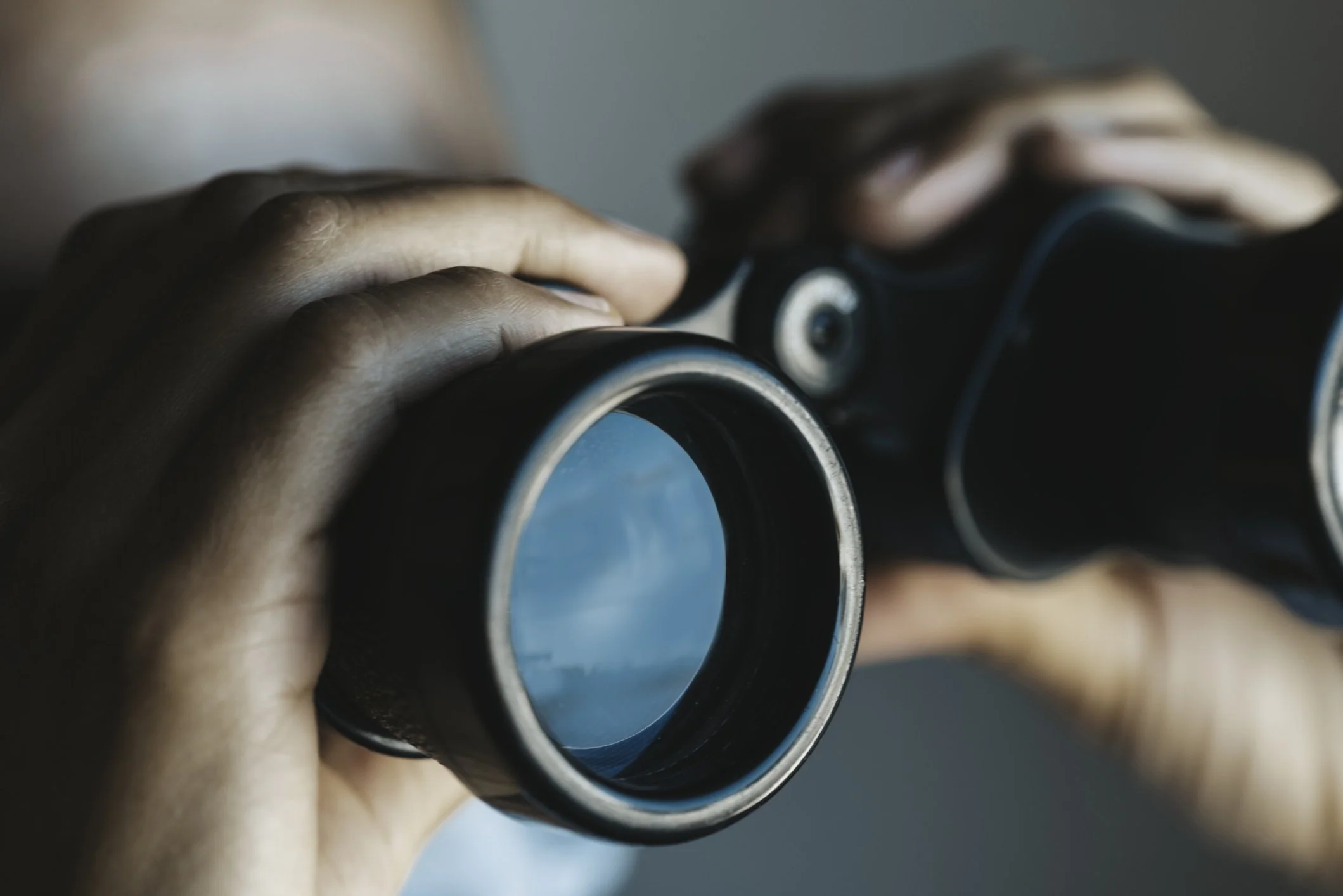 Close-up of a person holding binoculars, looking through them.