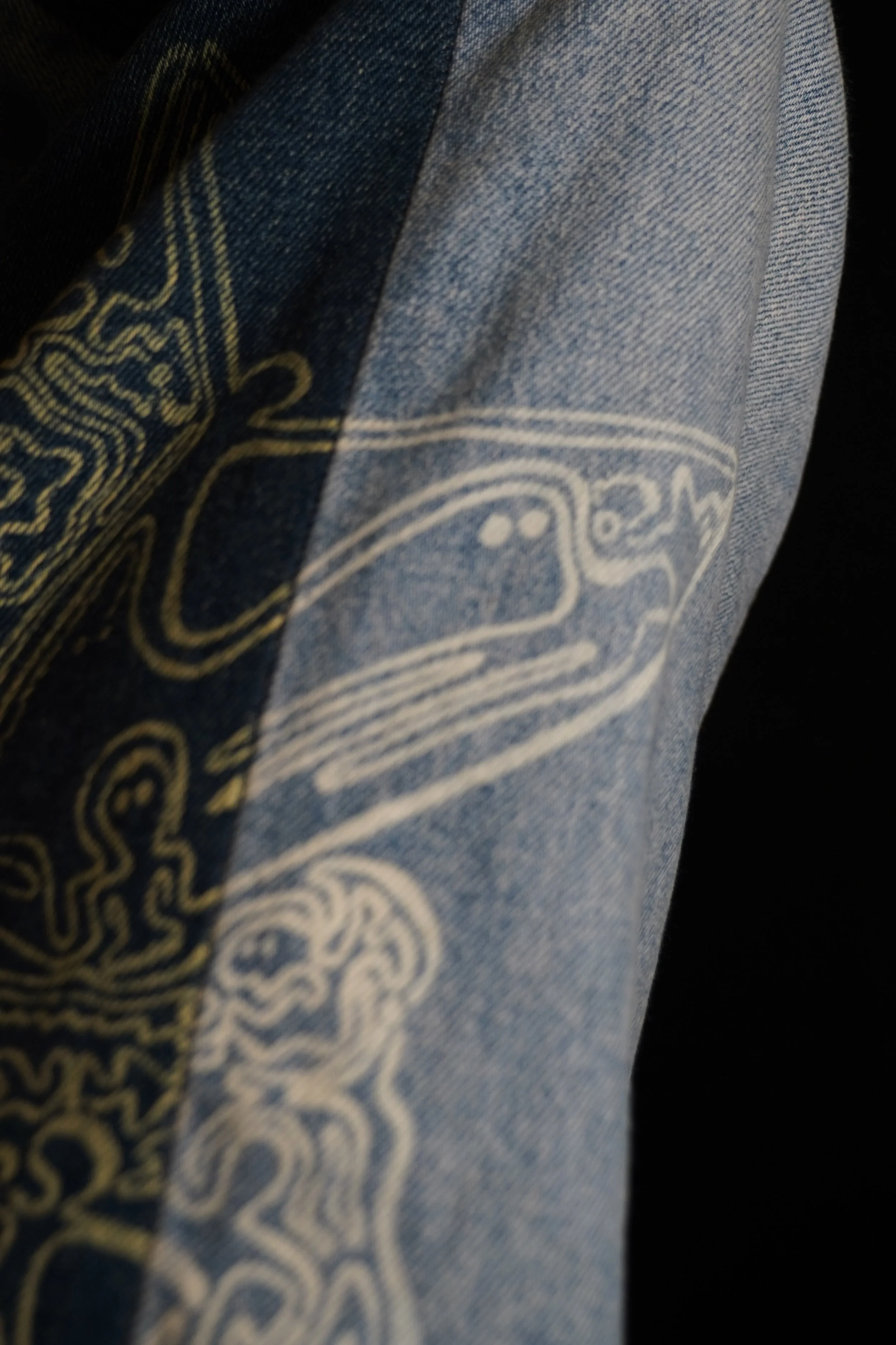 Close-up of a denim fabric with a design printed in light color, possibly part of clothing or accessory.