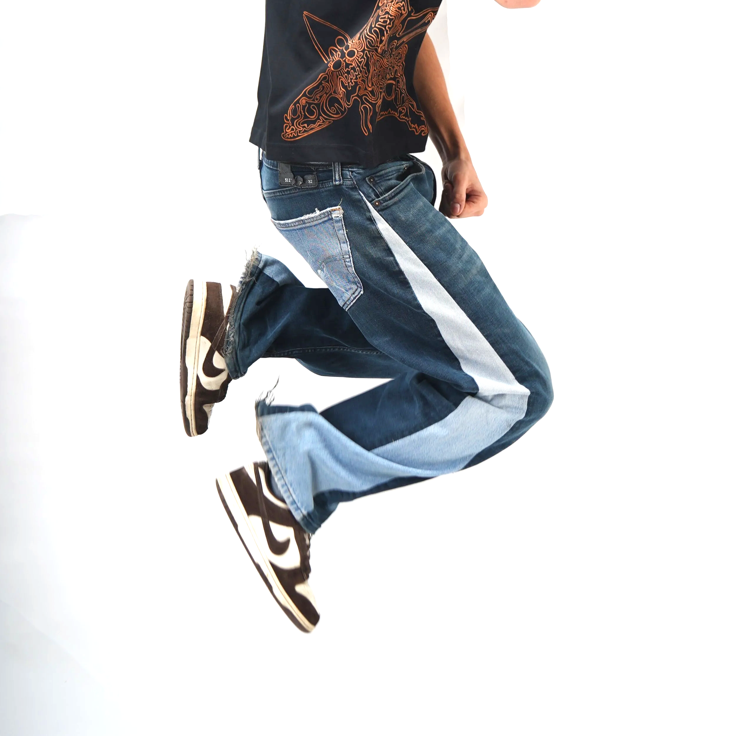 Person mid-jump wearing baggy jeans, a graphic T-shirt, and Nike sneakers against a plain white background.