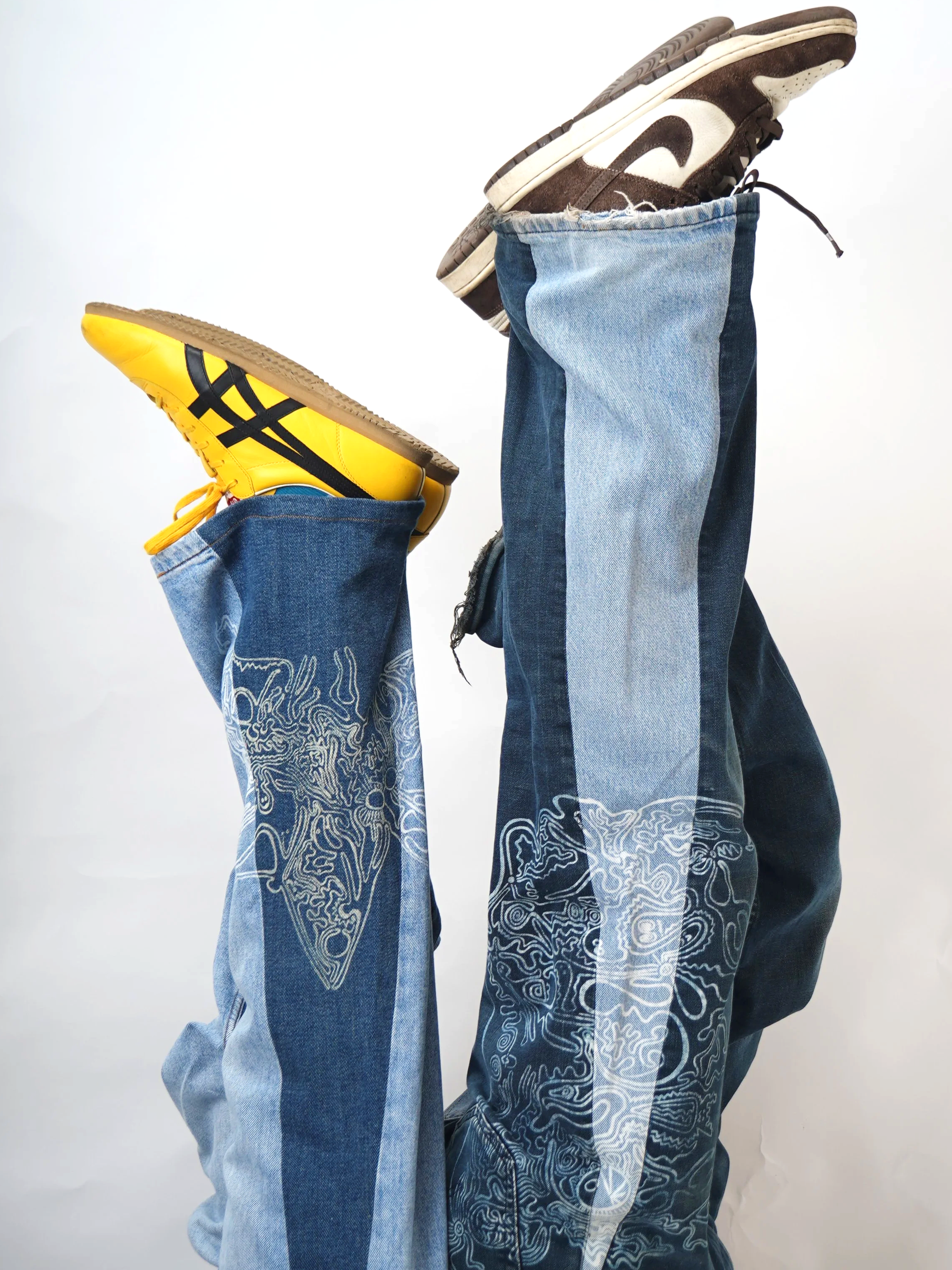 Two people with ripped jeans, one wearing yellow sneakers and the other wearing brown and white sneakers, with their legs lifted upward.