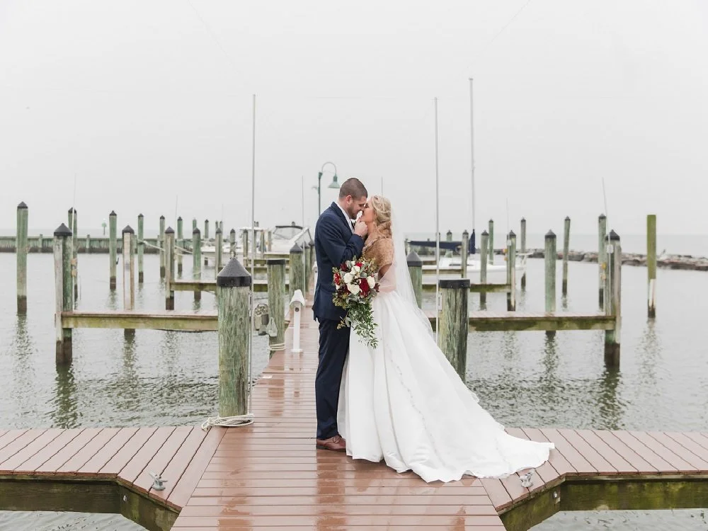 Couple taking photos on docks of Marina for nautical setting. 