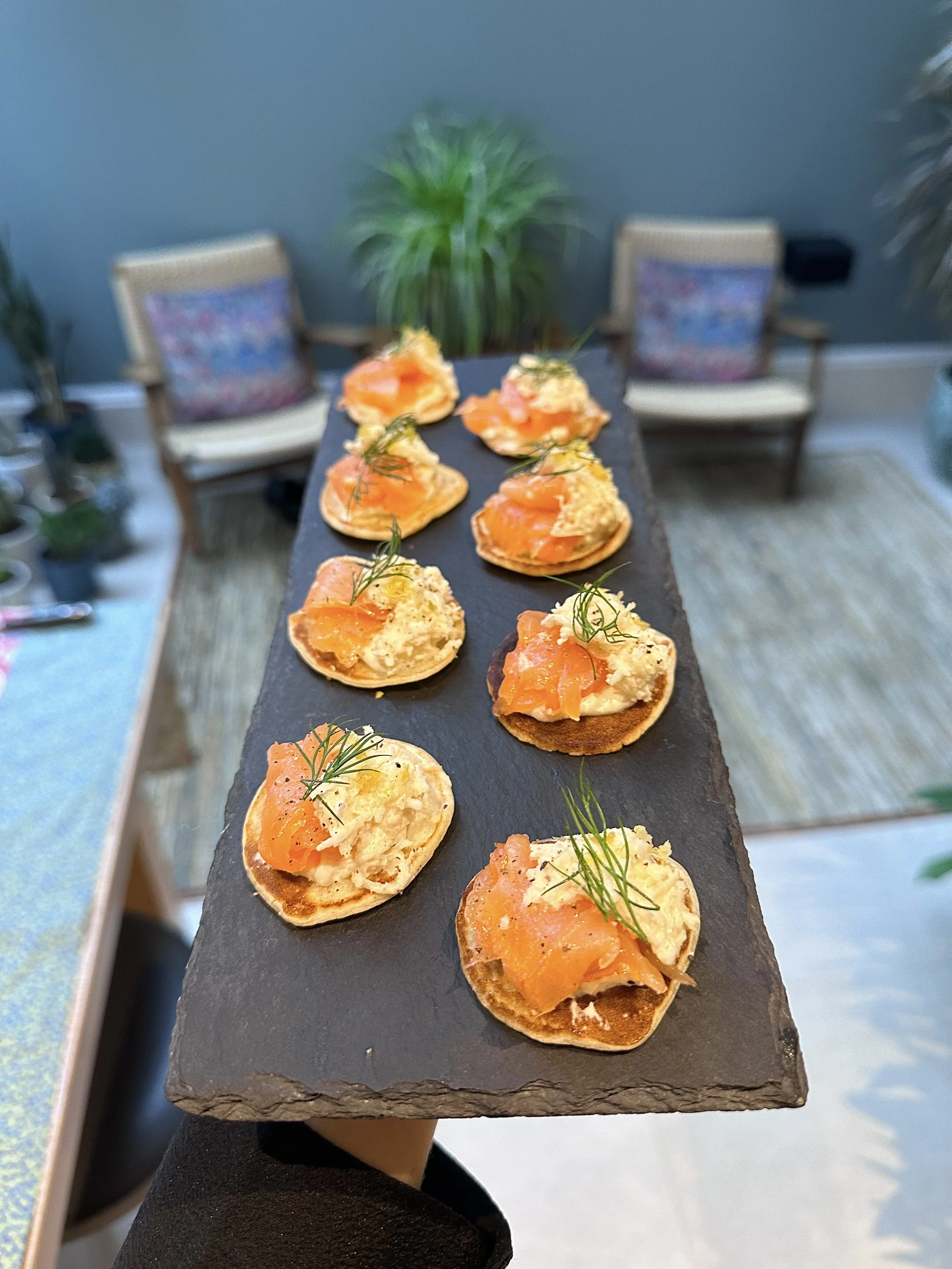 Slate platter with smoked salmon and cream cheese canapés, garnished with fresh dill.