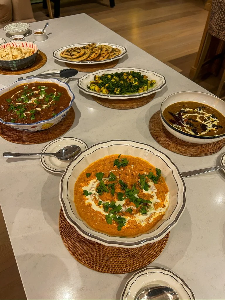 Assorted Indian dishes on a dinner table, including curry, rice, flatbread, and vegetables.