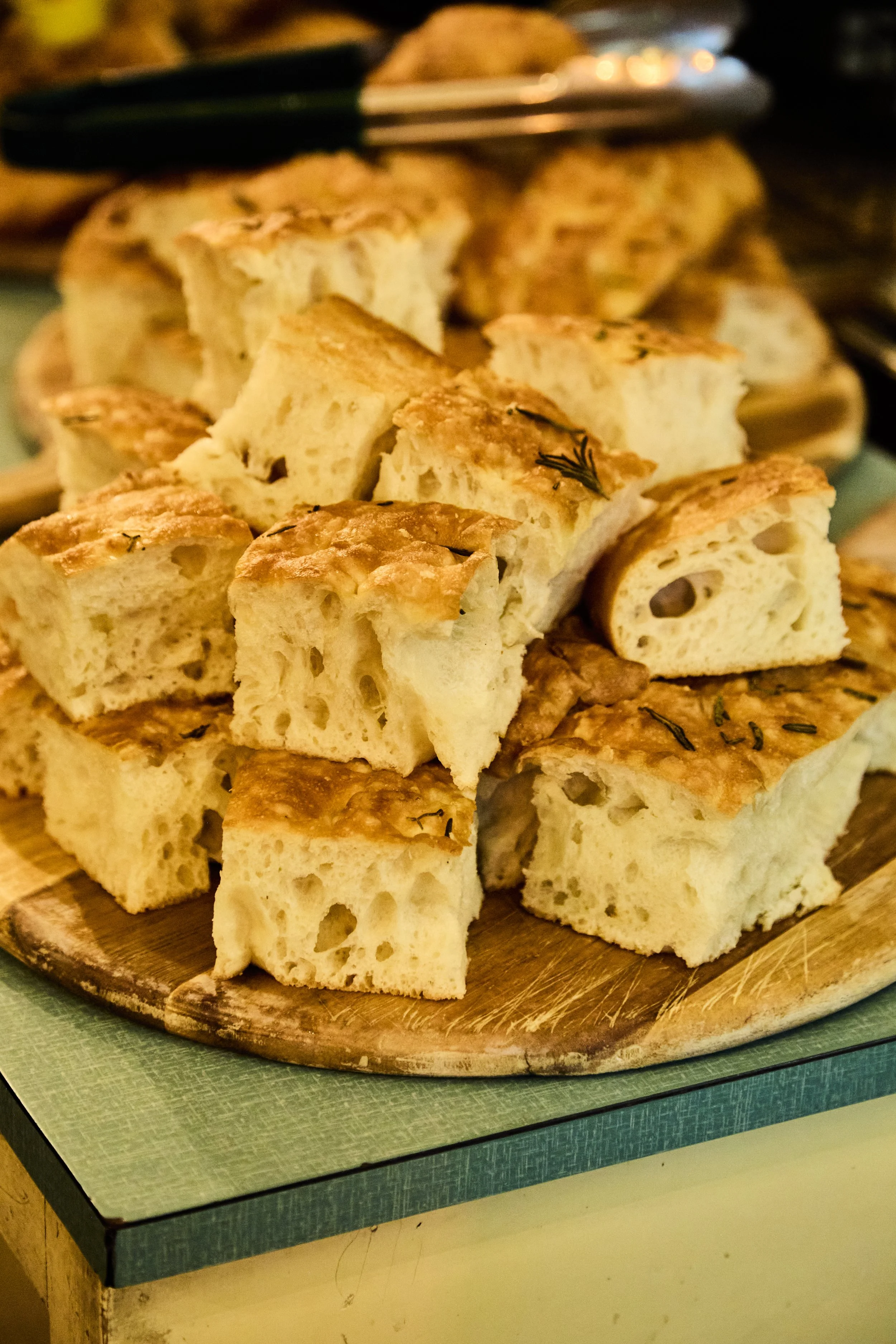 A wooden platter of chopped focaccia bread with herbs.