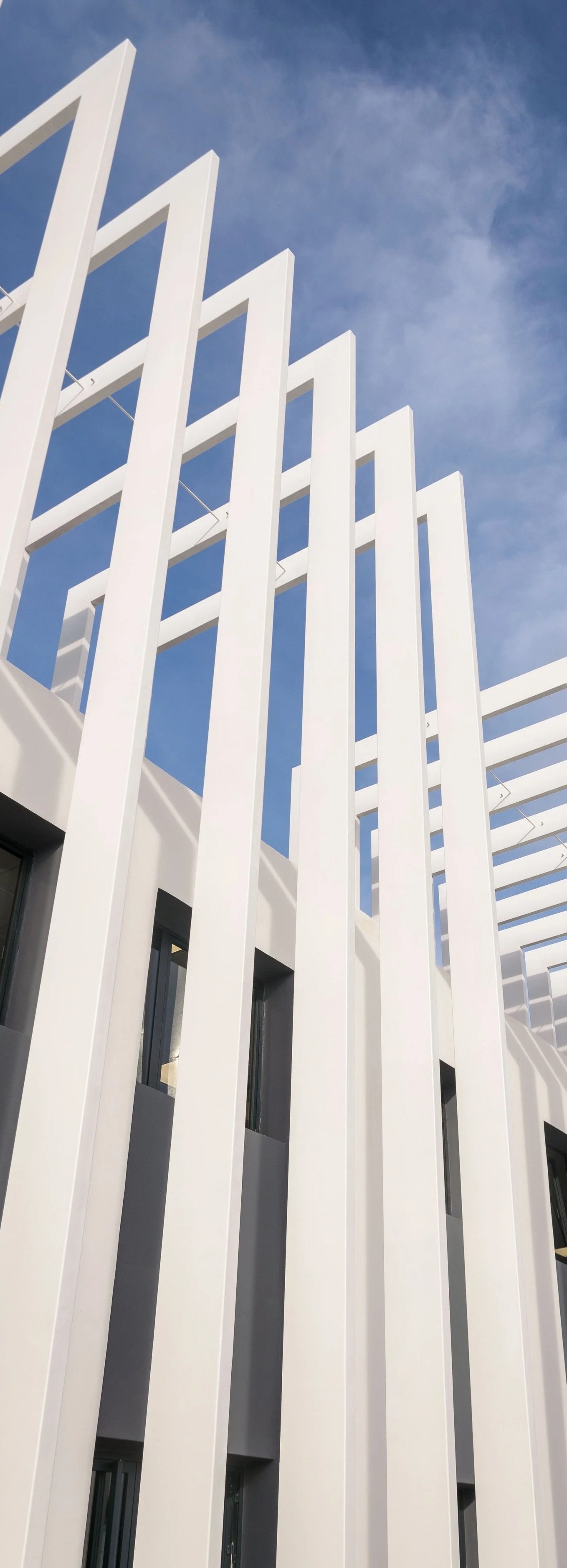 White architectural facade with vertical fins against the sky