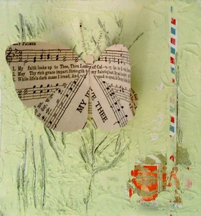 A heart shape made from folded sheet music on a textured, light-colored wall with a striped tape measuring pole nearby.