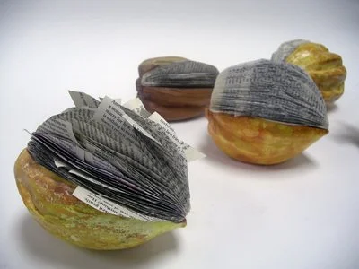 Three pieces of fruit with paper back book pages inserted in the splits around their tops 