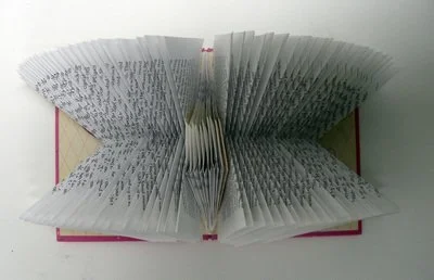 Rescued old book with pages folded creating an abstract repeating pattern.