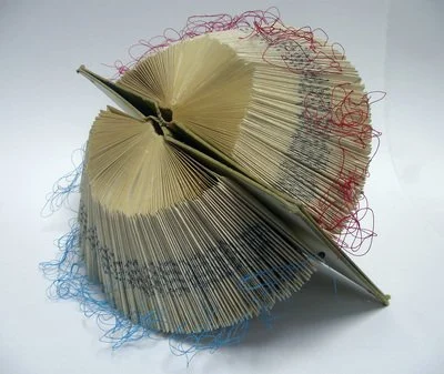 Rescued old book with pages folded creating an abstract repeating pattern. with thread