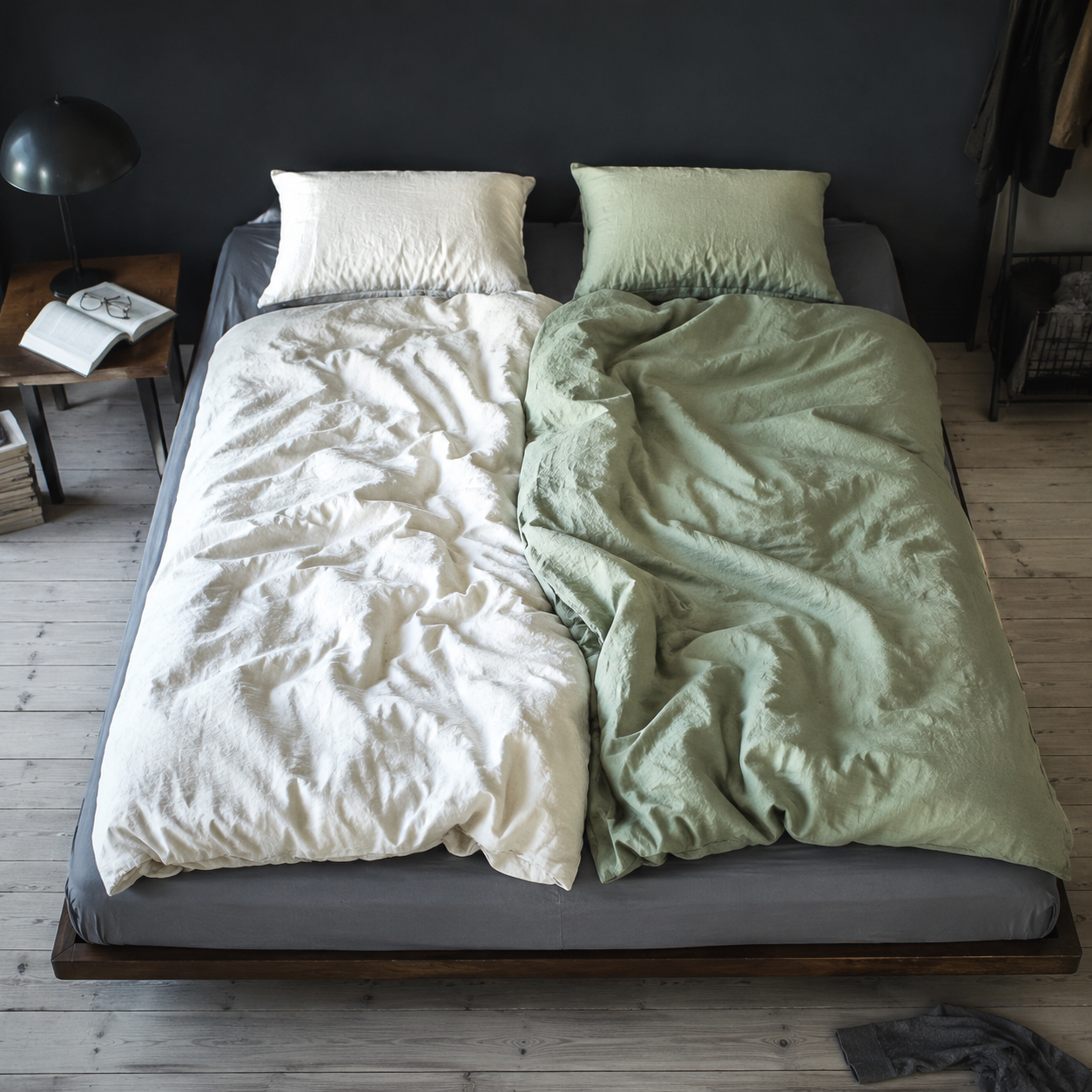 One continuous bed with two separate duvets in warm ivory and pastel sage green, with exactly one pillow per side.
