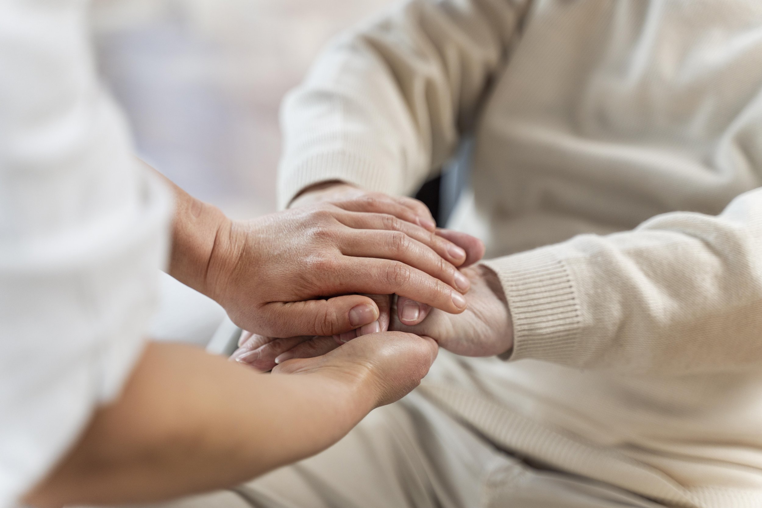 Multiple hands gently holding and supporting each other, symbolizing care and compassion.