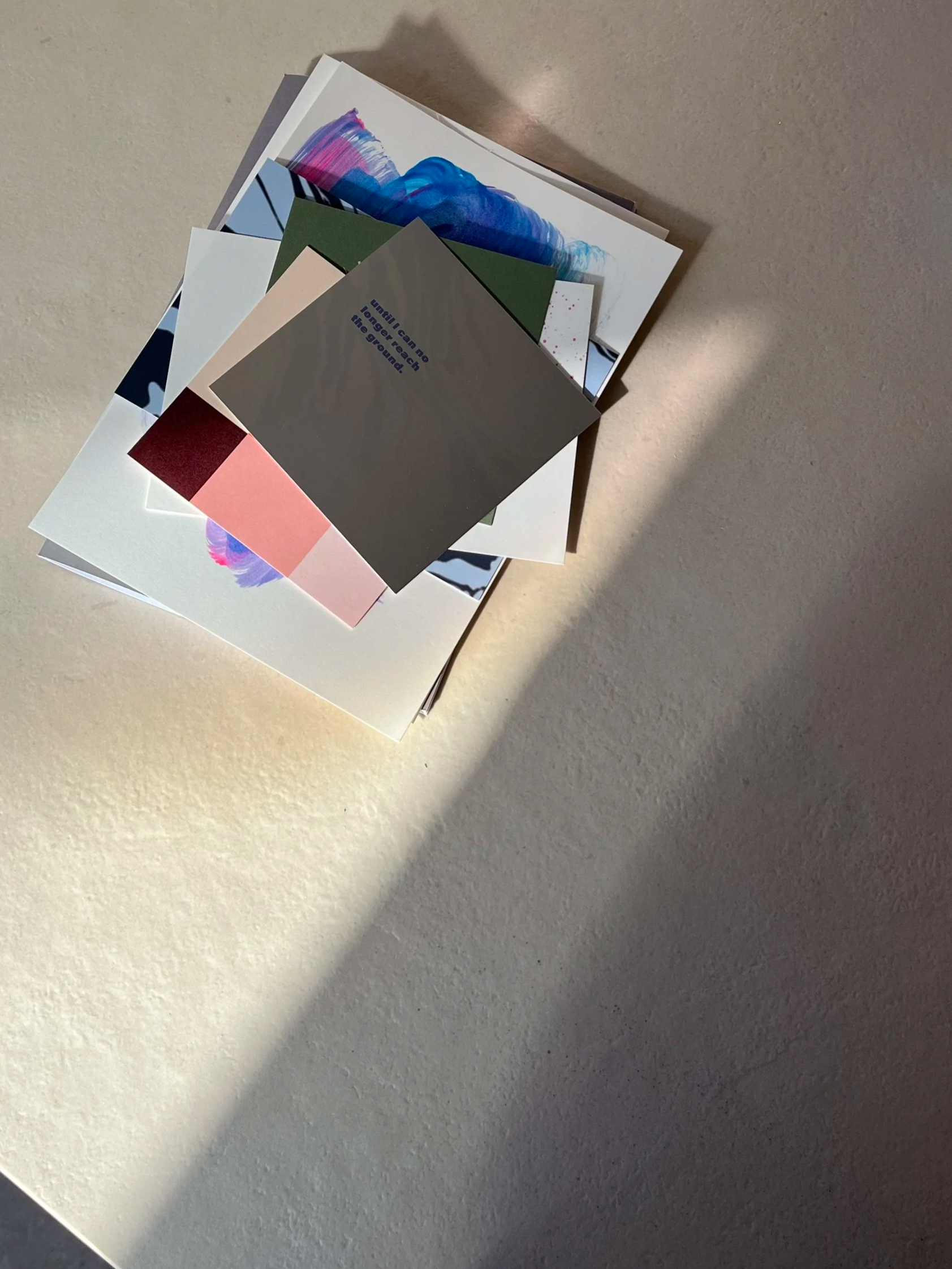 Haufen von verschiedenen bunten Papiersorten auf einer weißen Oberfläche, teilweise im Schatten.