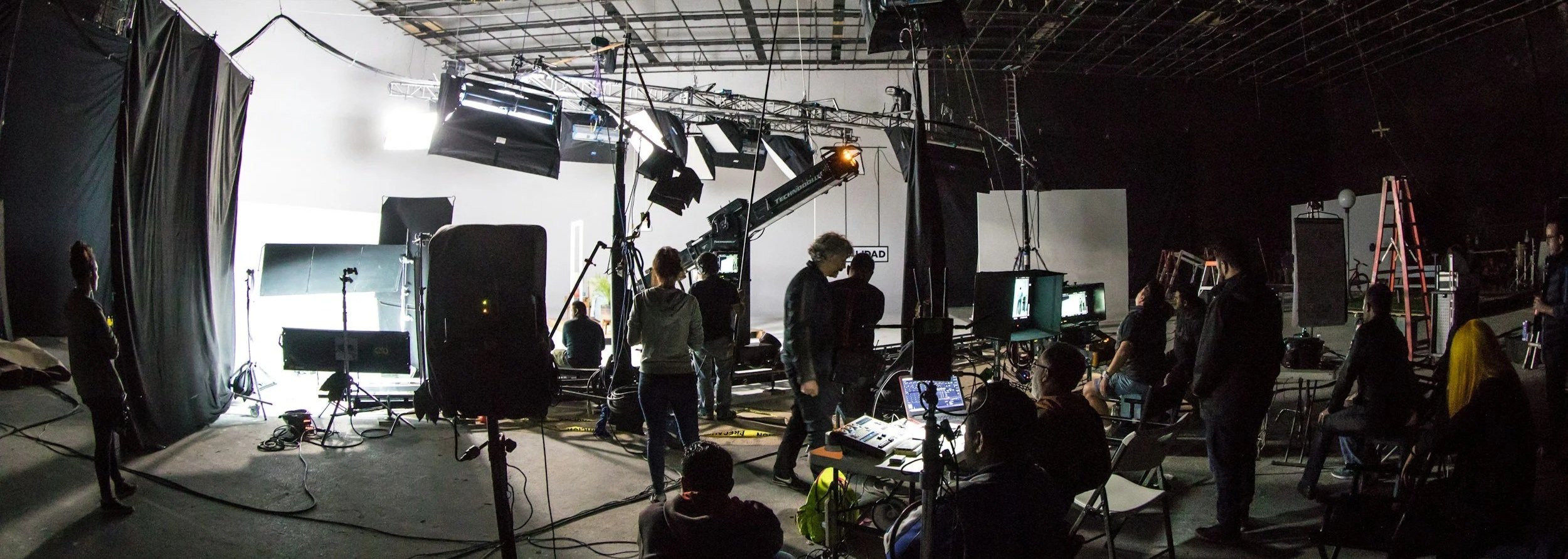 Large Crew shooting a piece with lighting and a camera jib in a studio space