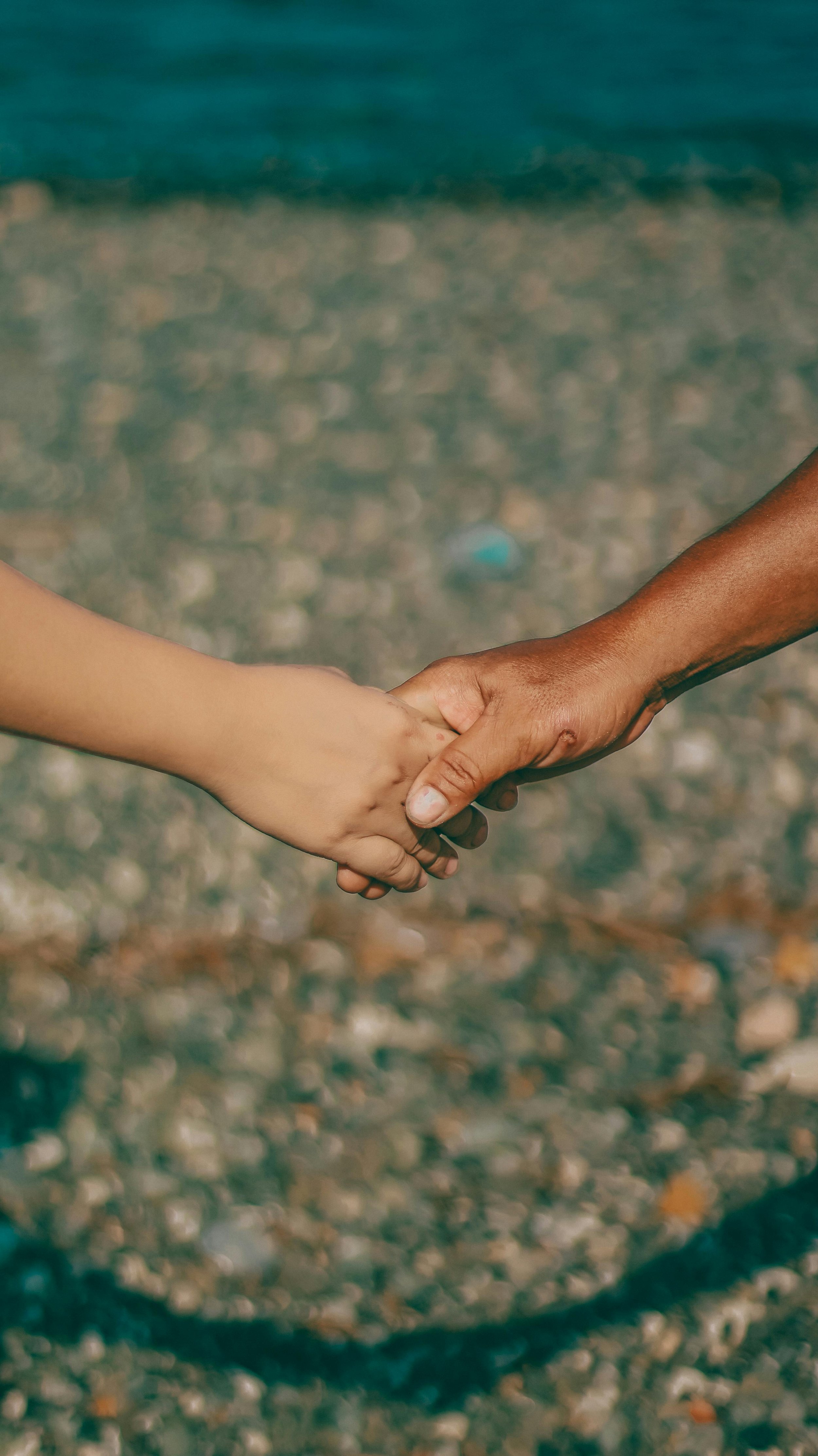 closeup of two hands holding on a beach