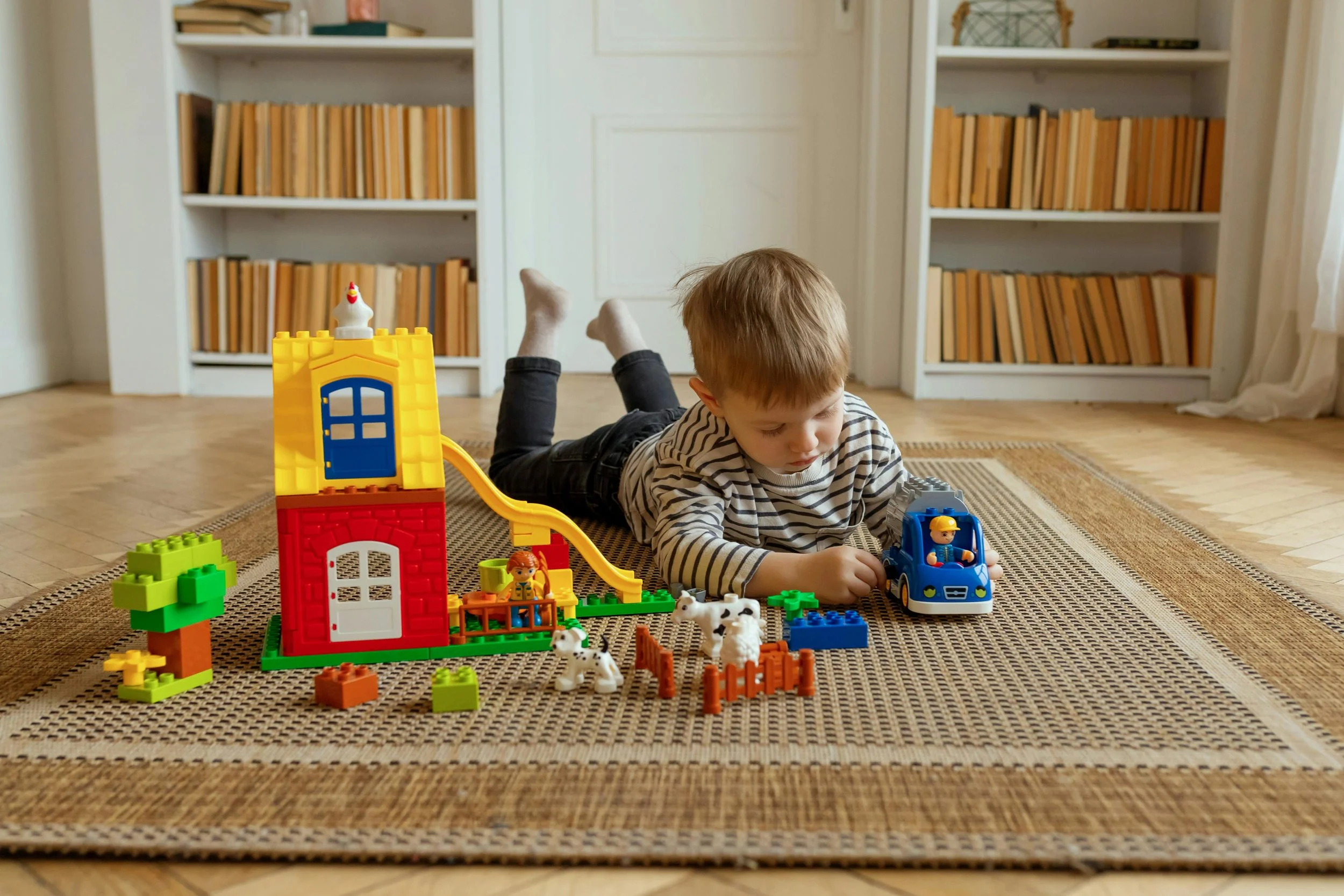 child laying on the floor playing with duplo legos