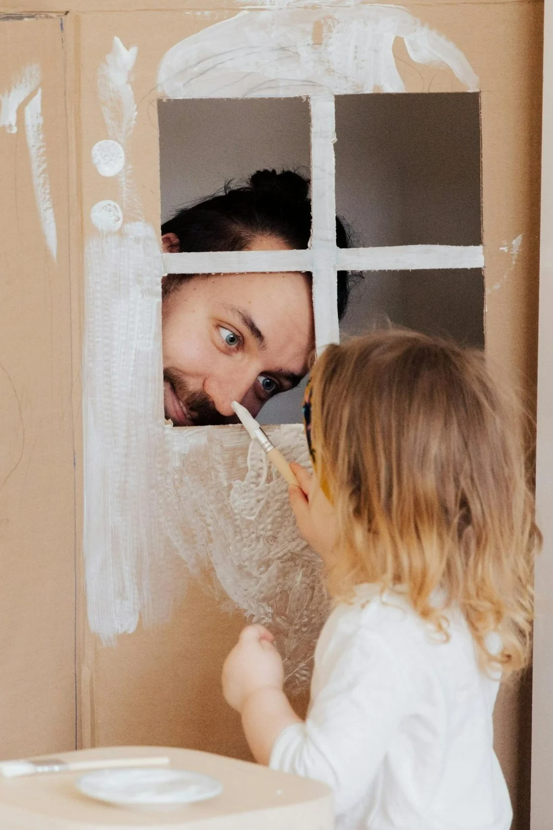 father and daughter playing in a cardboard house