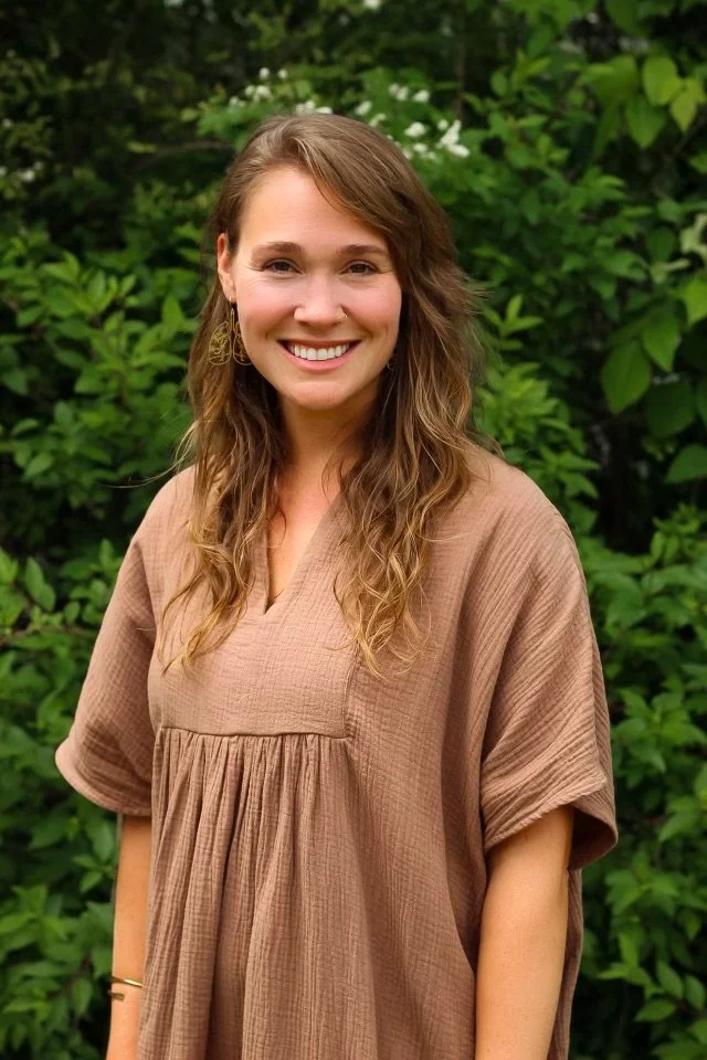 Woman smiling in front of green foliage