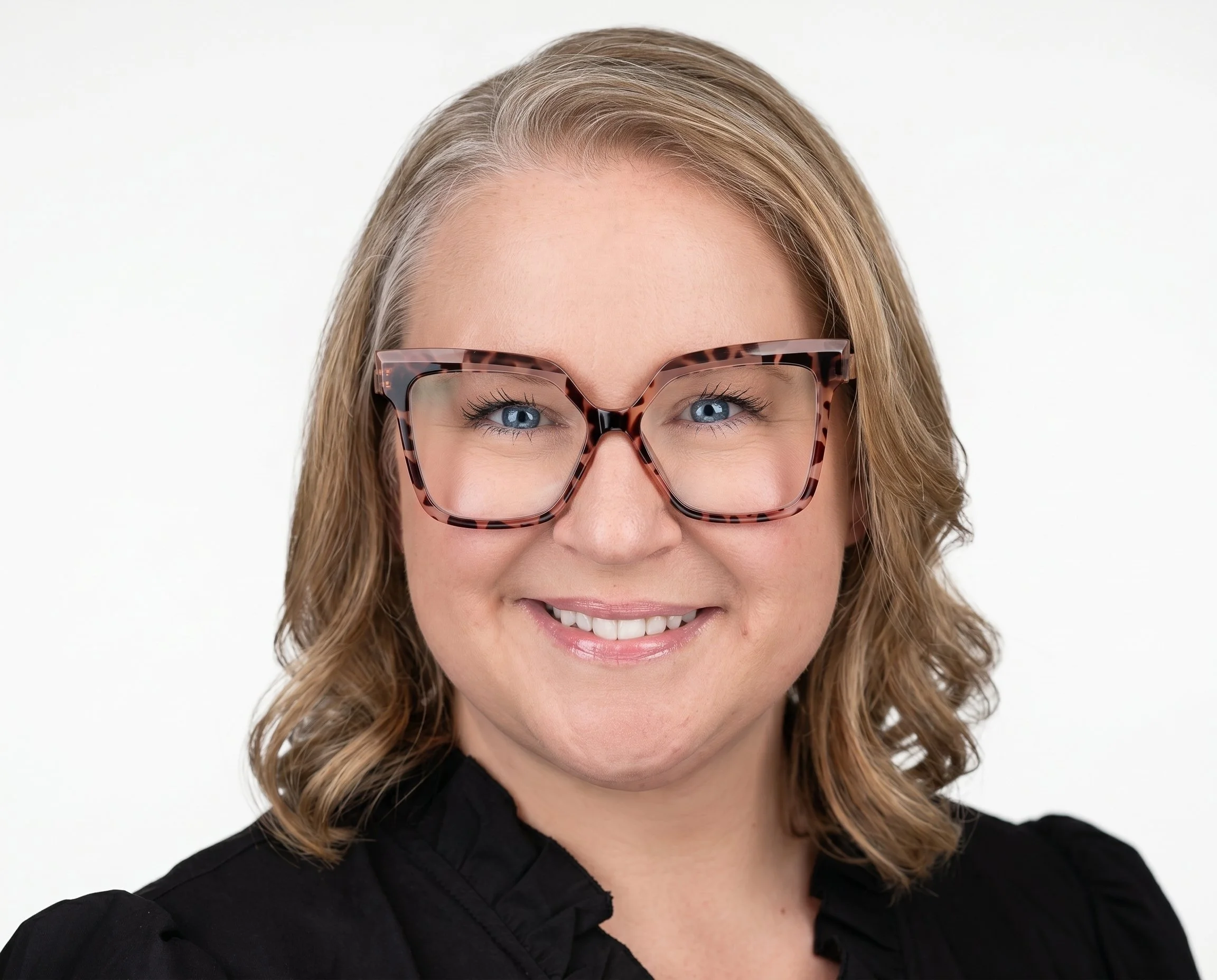 Close-up of Terri Hutchings, a woman patient advocate working with PatientAdvocates.ca, who is smiling with blonde hair, large tortoiseshell glasses and a black shirt.