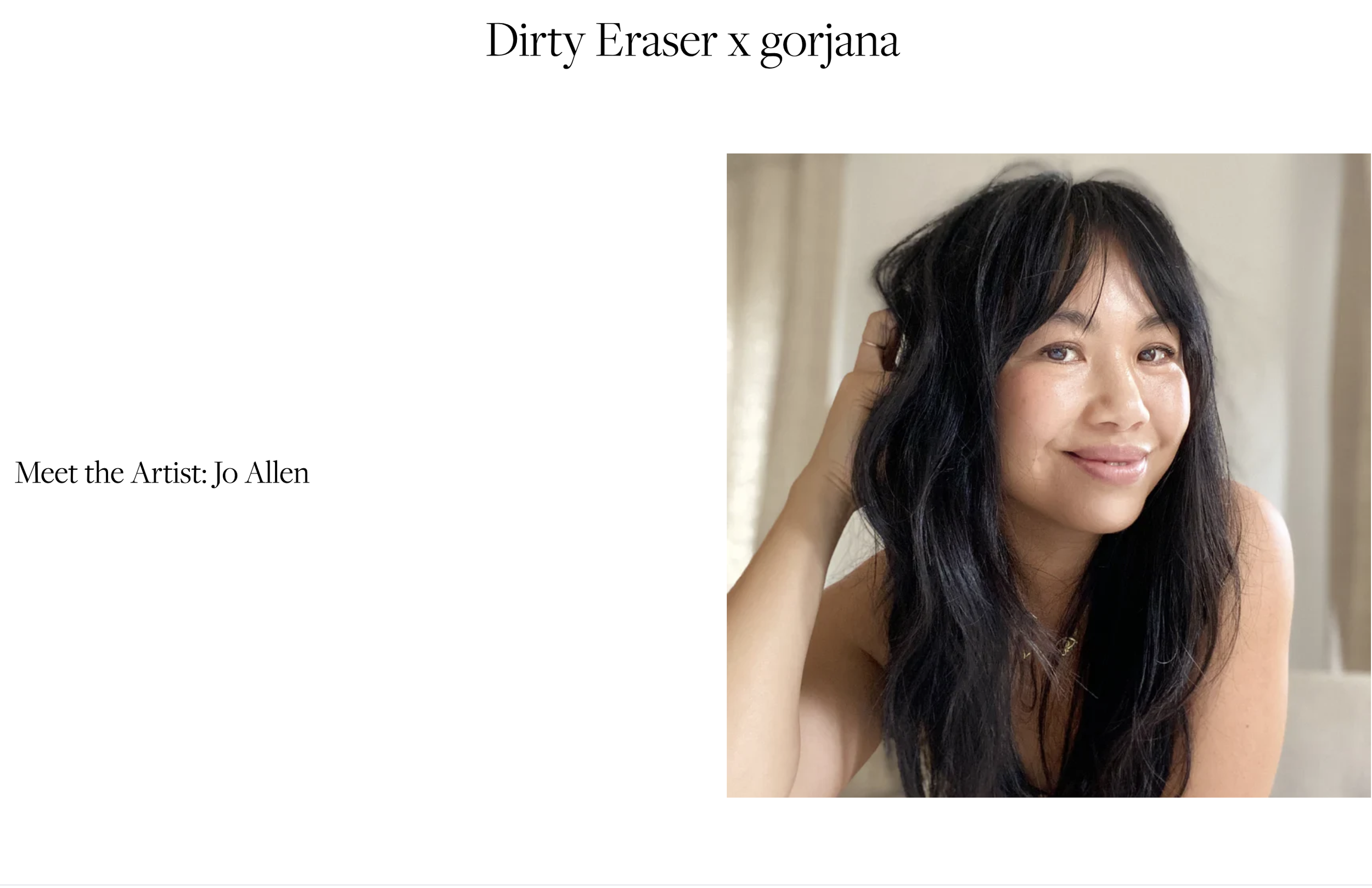 A woman with long black hair smiling and touching her hair with her hand. She has a light skin tone and is in an indoor setting.