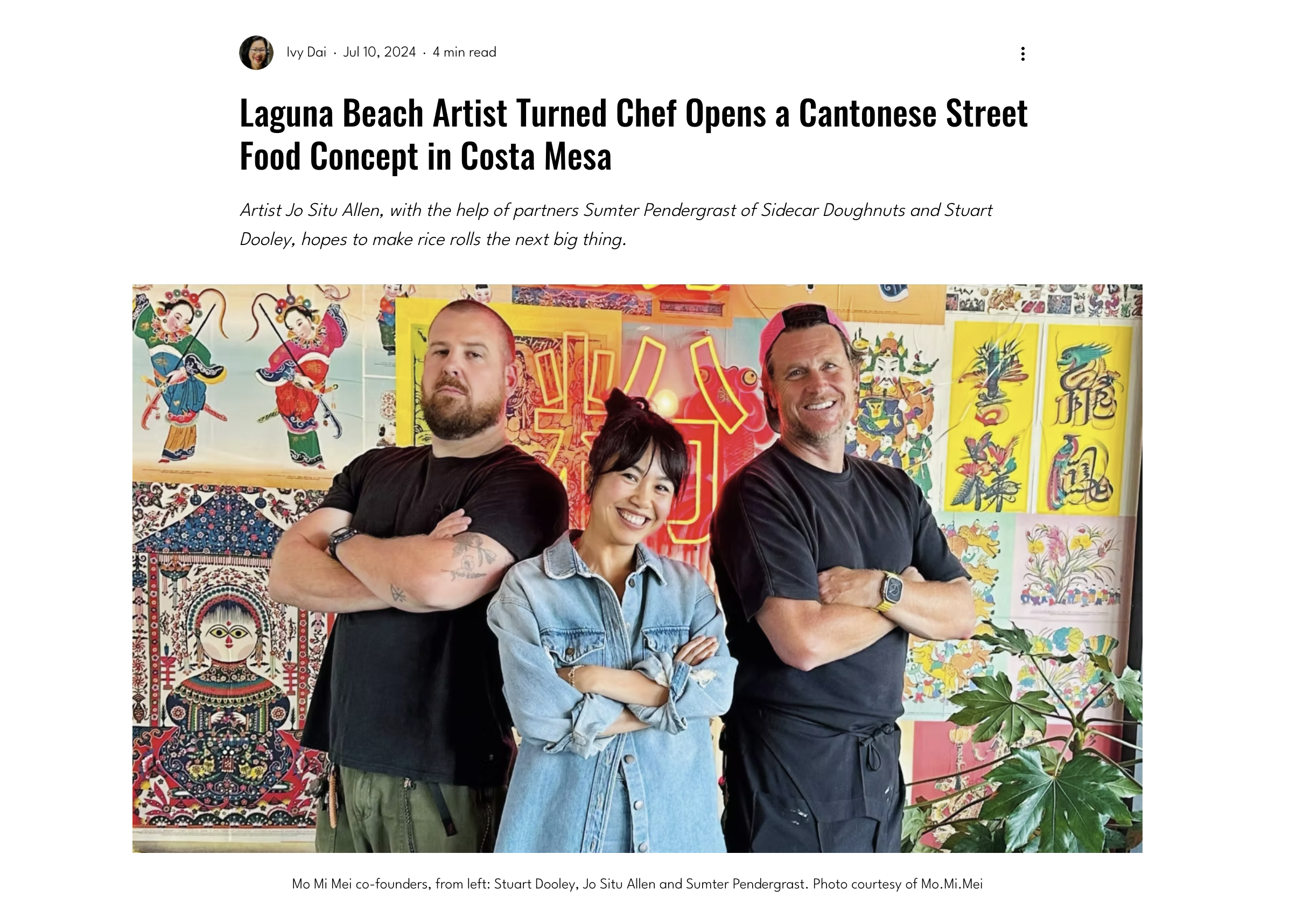 Three people standing in front of colorful Asian-themed artwork, with two men on either side and a woman in the middle, all with arms crossed.