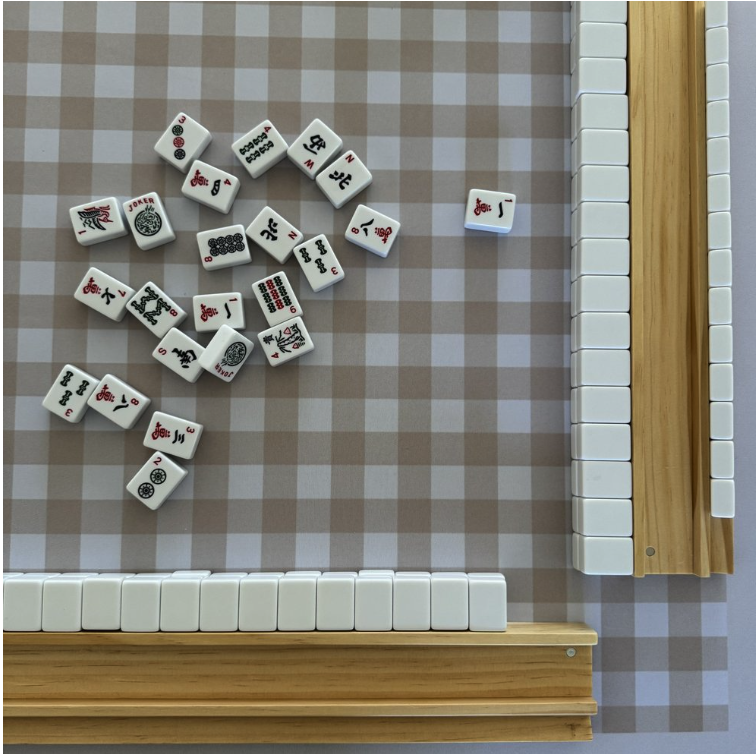 Mahjong tiles on a checkered tablecloth with wooden racks