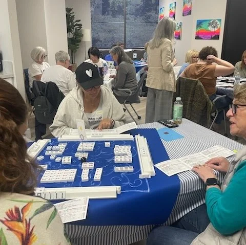 Beginners American Mahjong teaching Mahjong as corporate team building tables of employees in a conference room, learning Mahjong