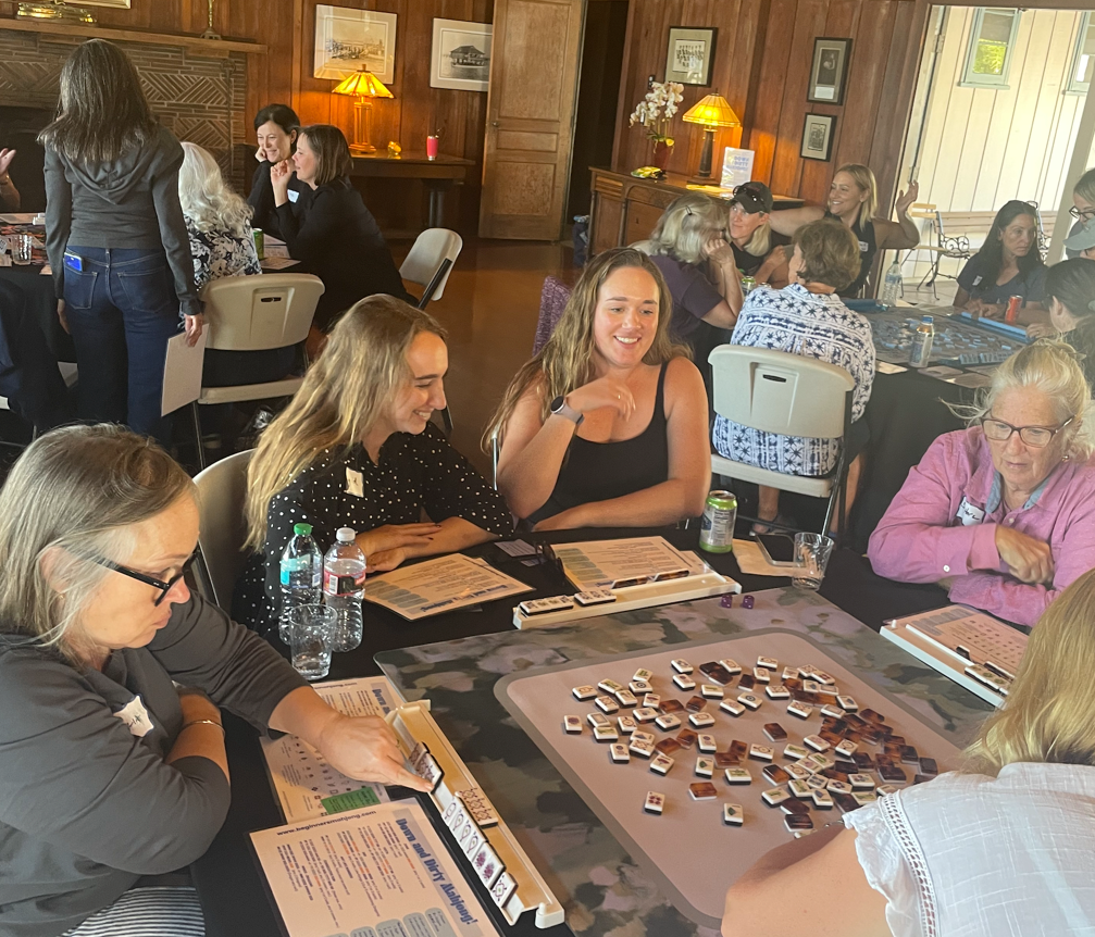 Beginners American Mahjong teaching Mahjong to several tables of people as part of a fundraising event.