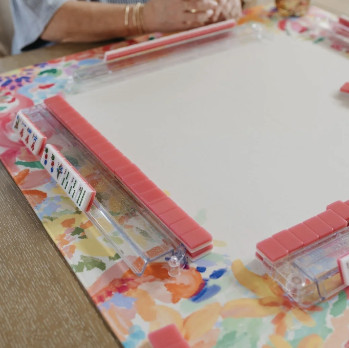 Mah Jongg Maven picture of a colorful, floral mat with pink backed mahjong tile walls.
