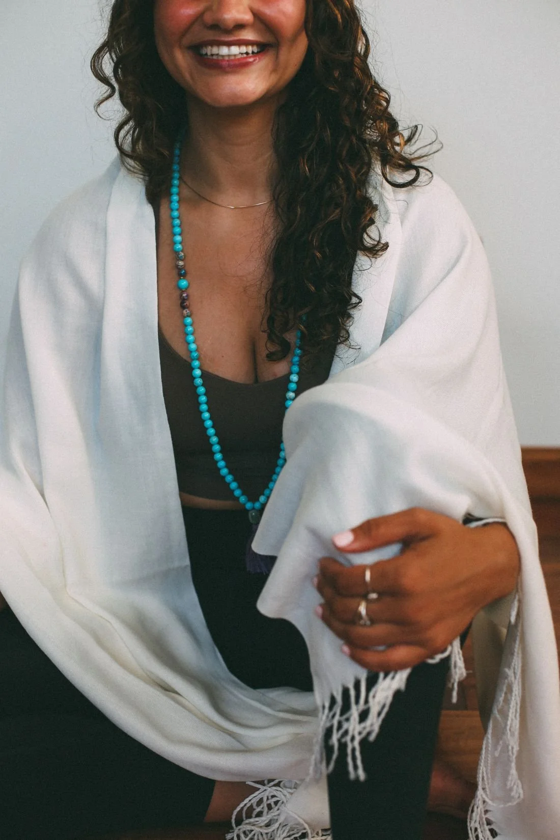 woman wearing teal blue mala necklace black yoga outfit and white reiki scarf