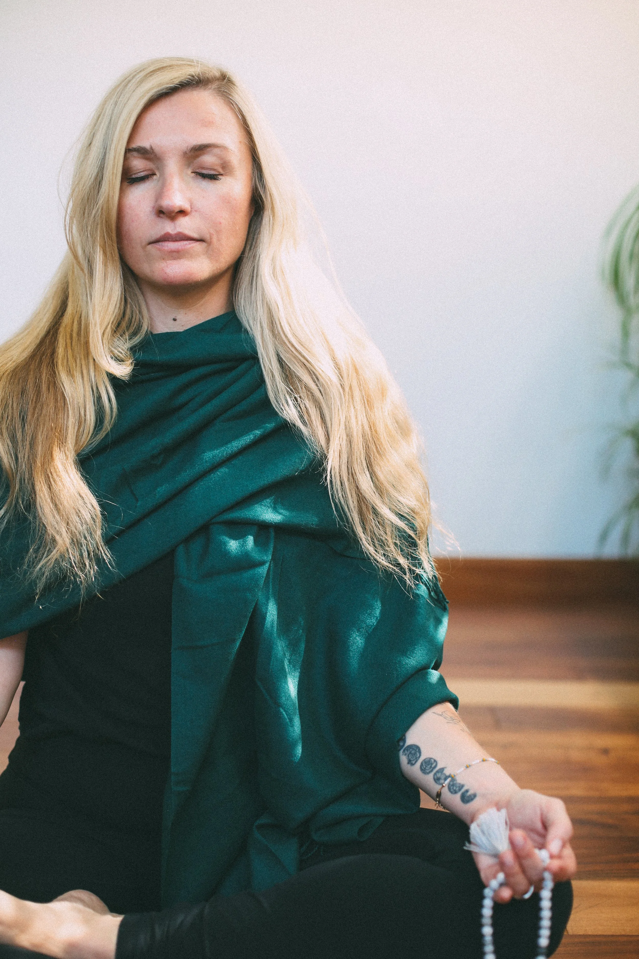 megan cannon meditating in green reiki scarf holding white mala in left hand