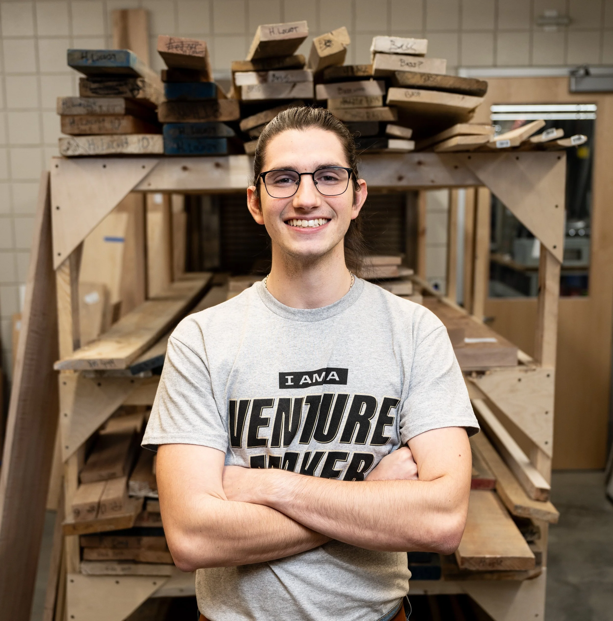 Guy standing in front of wood pallets with arms crossed.