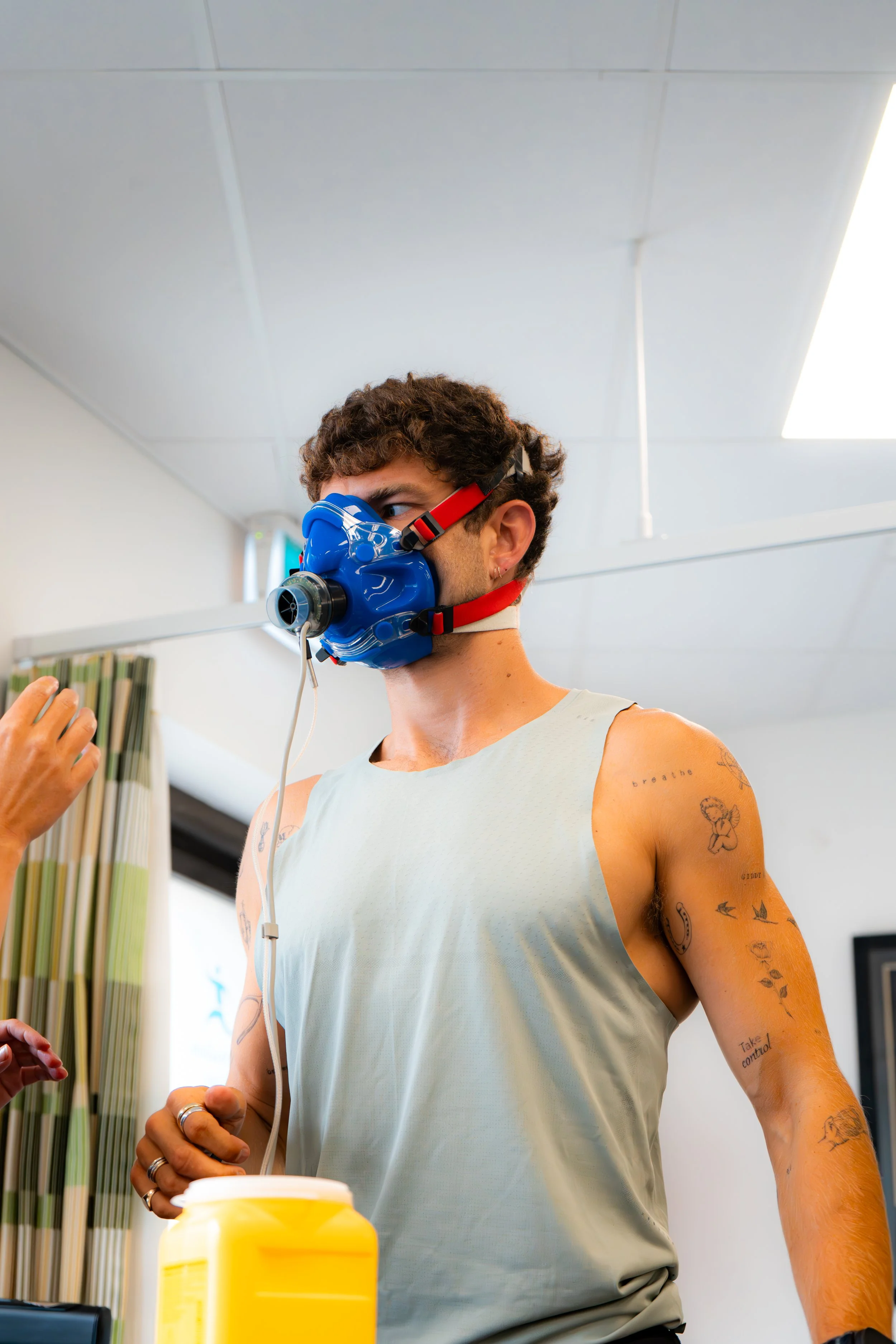 Person wearing a blue respiratory mask undergoing fitness testing in a gym setting.
