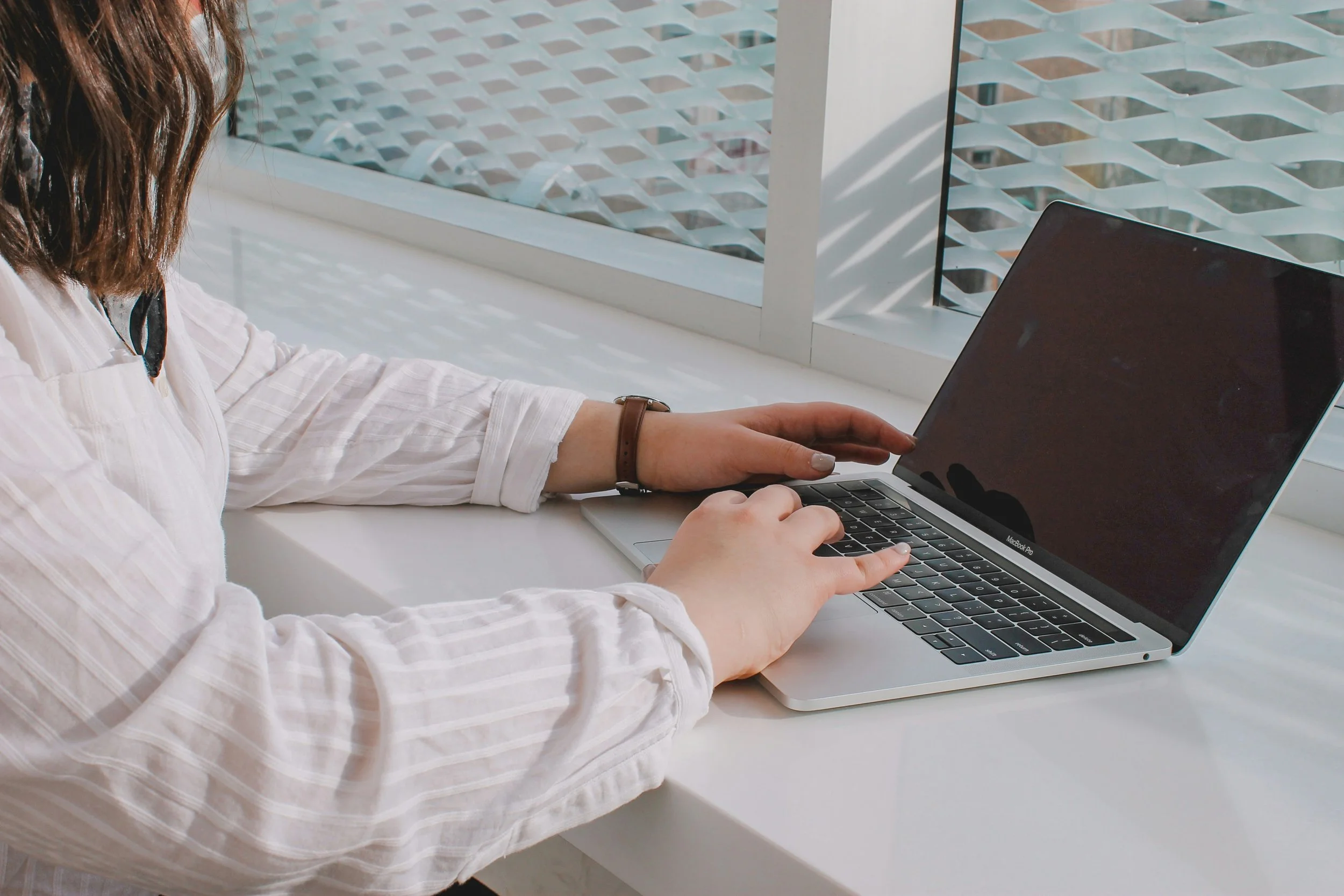 Person working on a laptop near a window, representing high-functioning perfectionism and burnout.