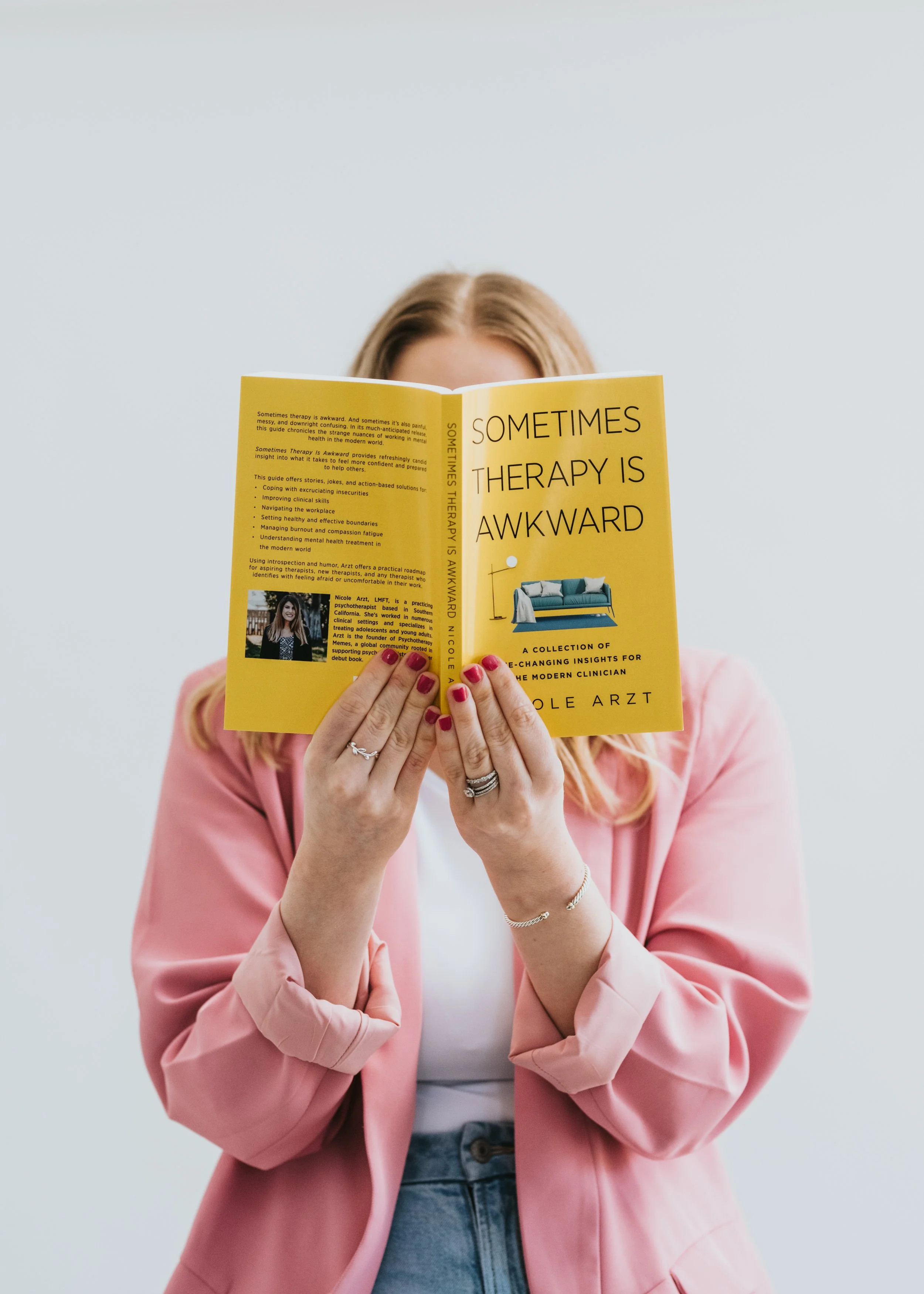 Victoria Williams holding a yellow book titled “Sometimes Therapy Is Awkward” in front of her face.