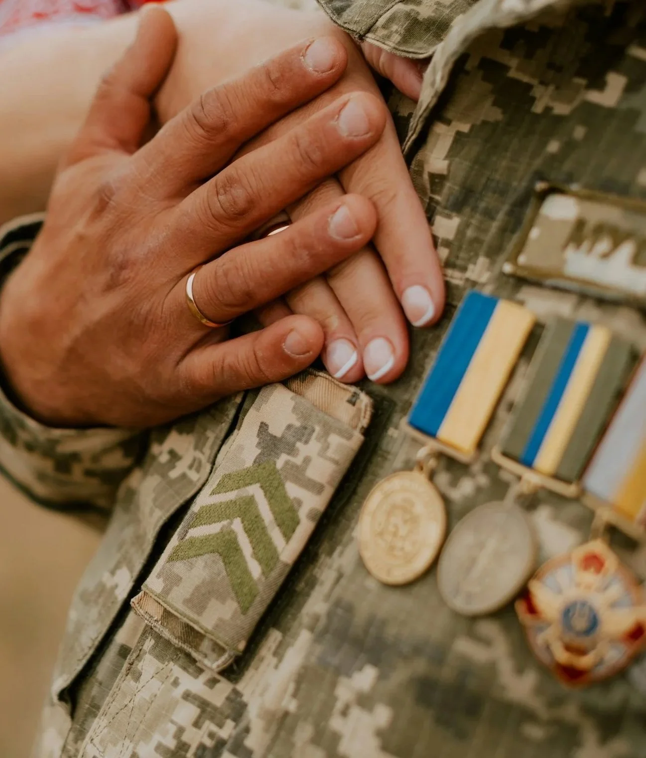 Close-up of hands resting on a military uniform with service medals, representing support for military and military-connected individuals.