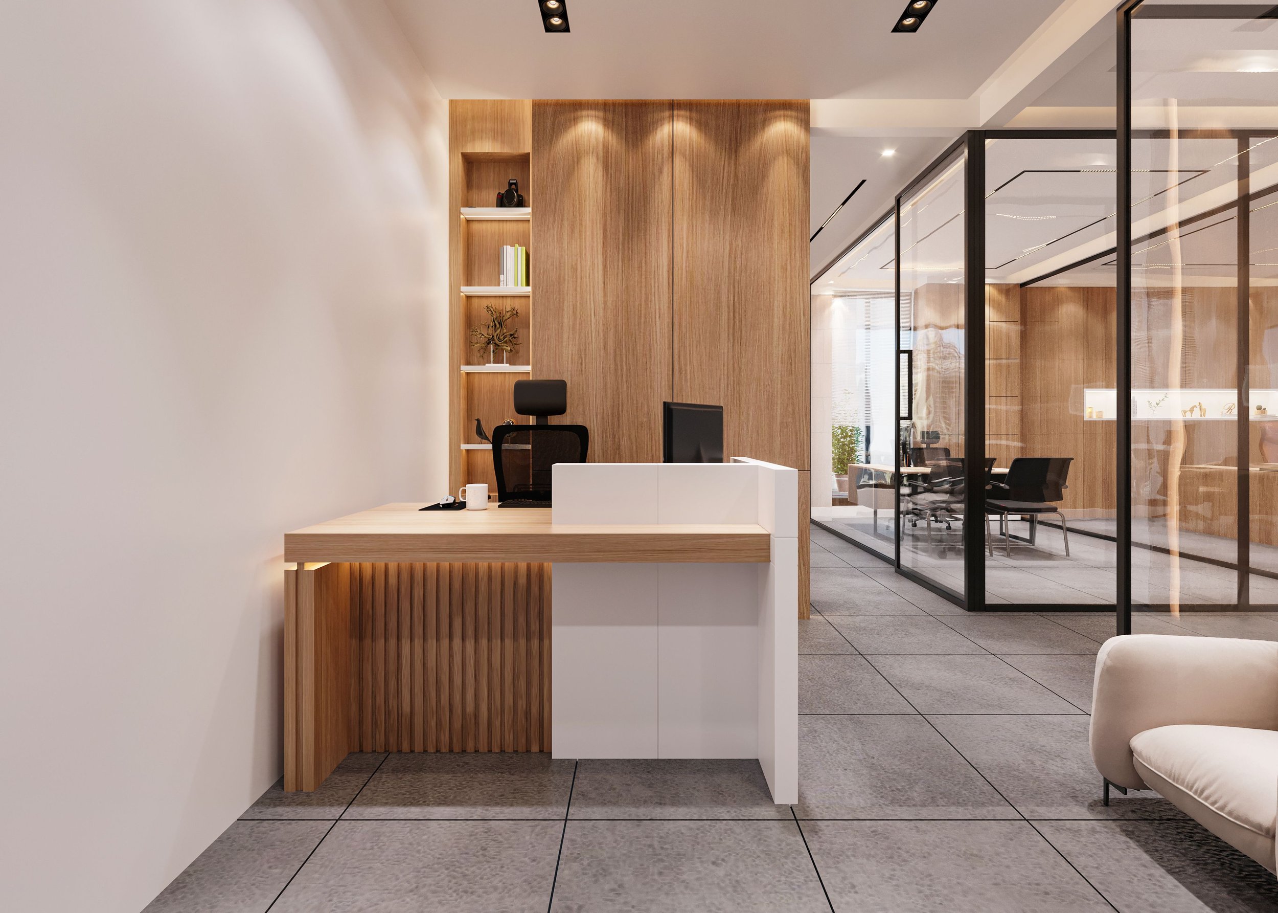 Modern office reception area with a wood paneled wall, a desk with a computer and coffee mug, and a glass-walled meeting room visible in the background.