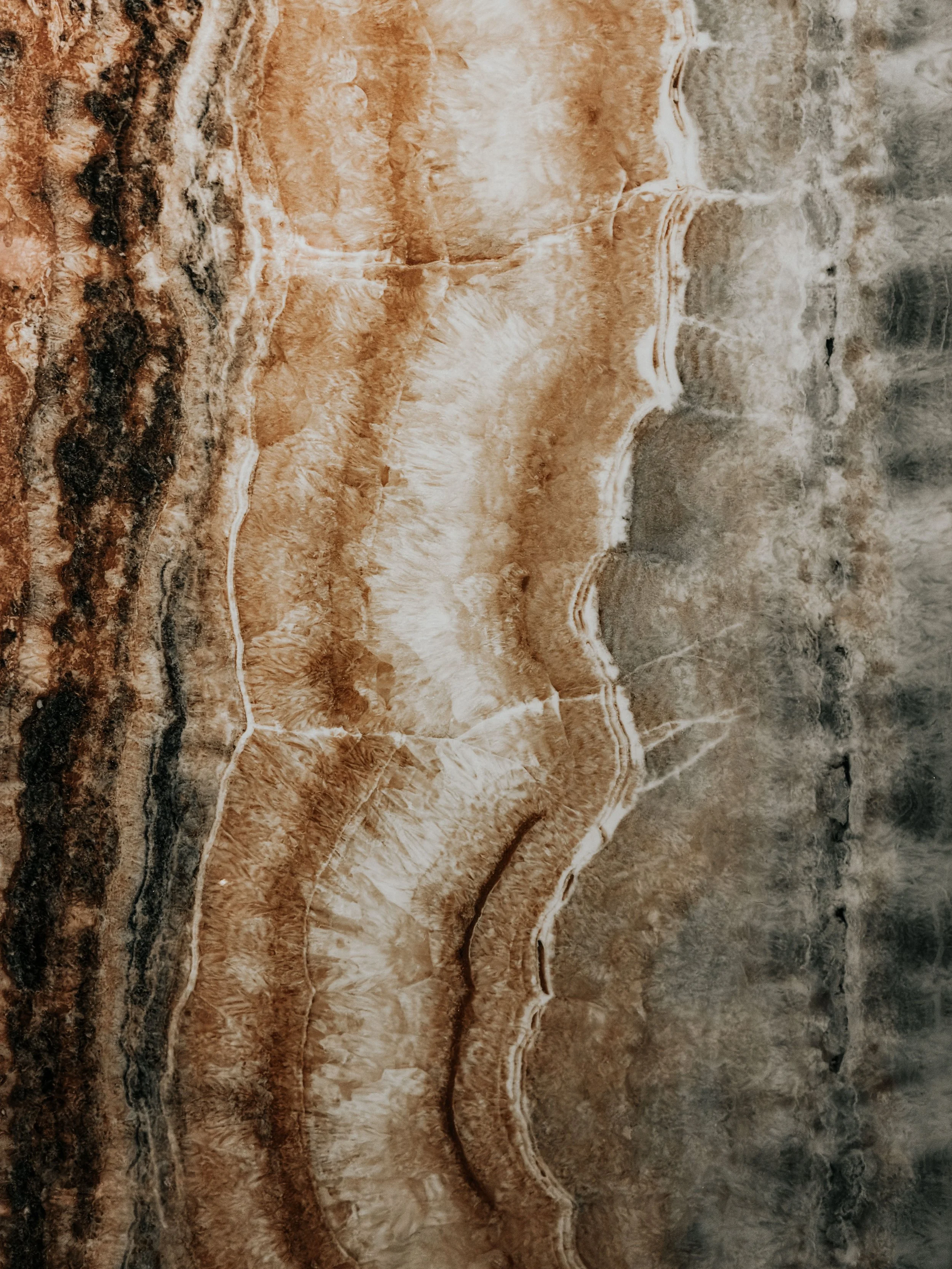 A detailed aerial view of a desert landscape with layered rock formations in shades of brown, tan, and beige.