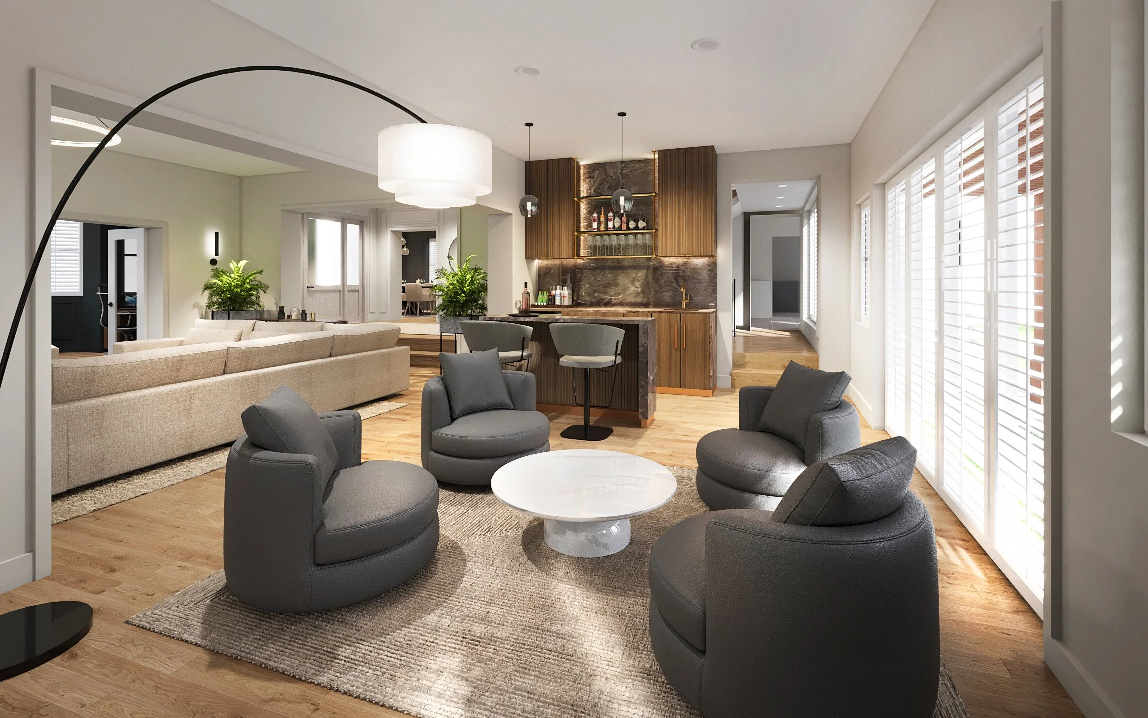 Living room with a beige sectional sofa, black round chairs, and a white coffee table on a beige rug. There are large windows with white shutters, and a bar area with wooden cabinets and bar stools. Some green plants and modern lighting fixtures are 