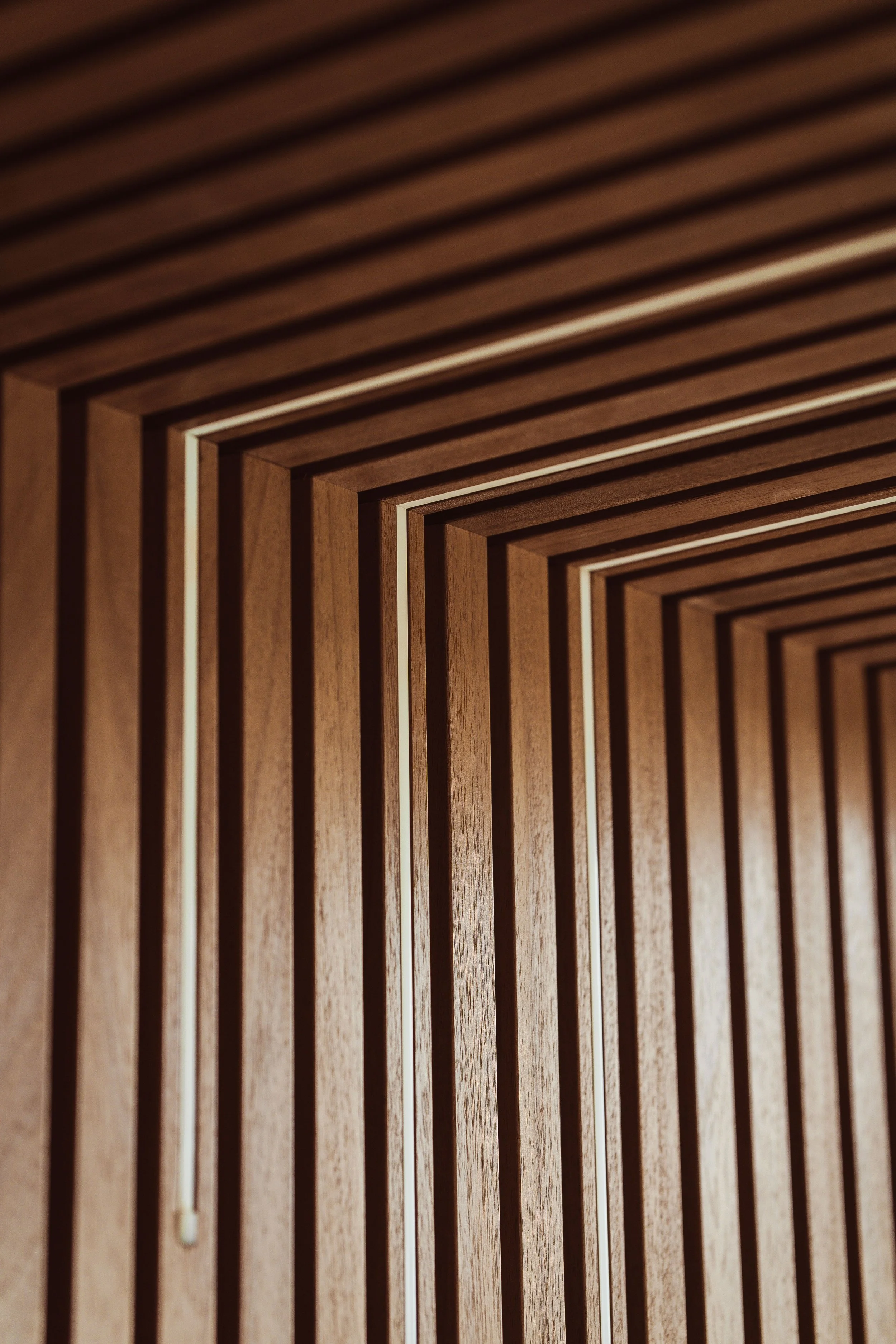 A close-up of a wooden geometric pattern made of parallel and intersecting wooden slats, creating a grid-like design with shadows.