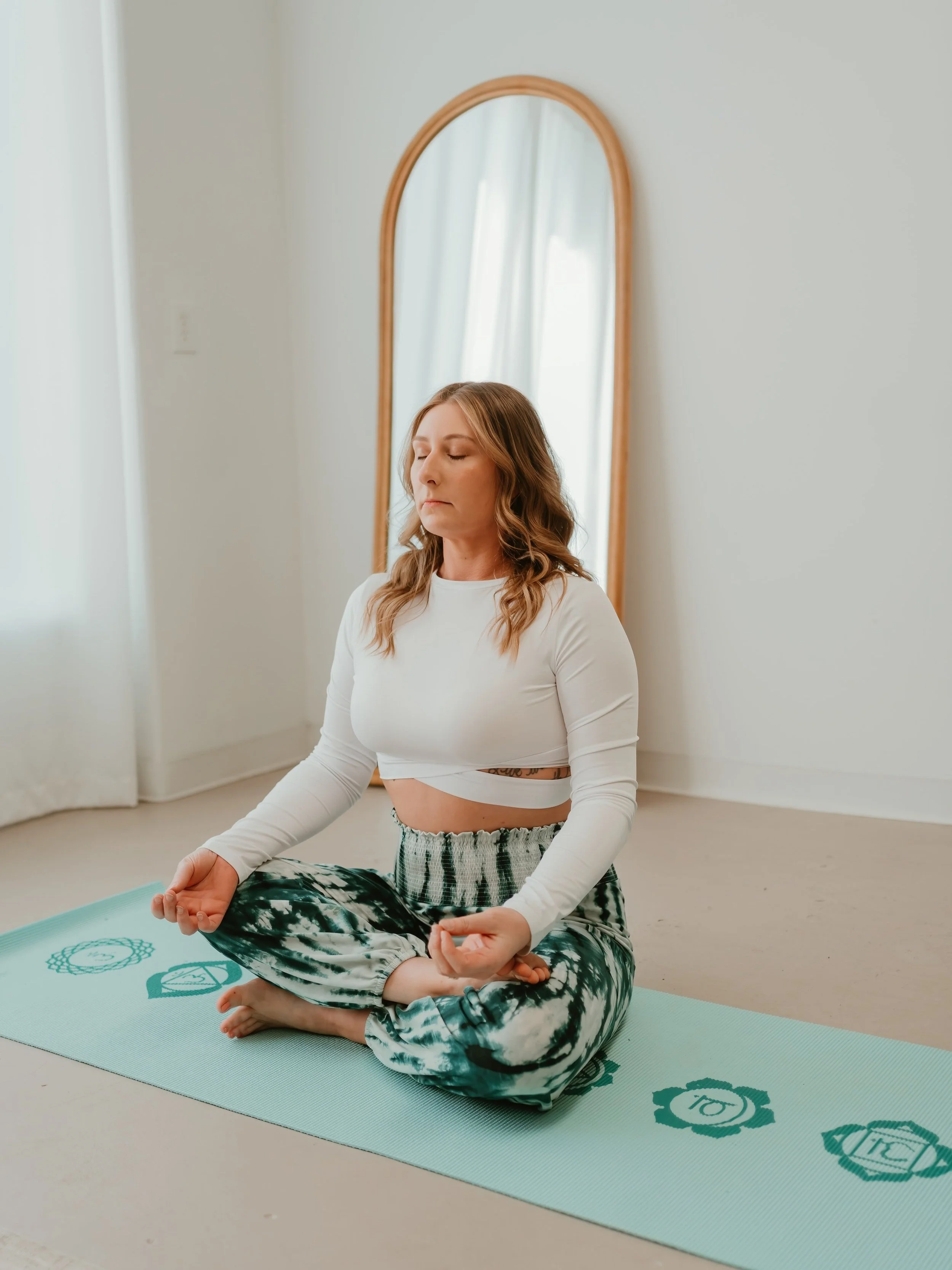A woman sitting cross-legged on a yoga mat in a meditation pose.